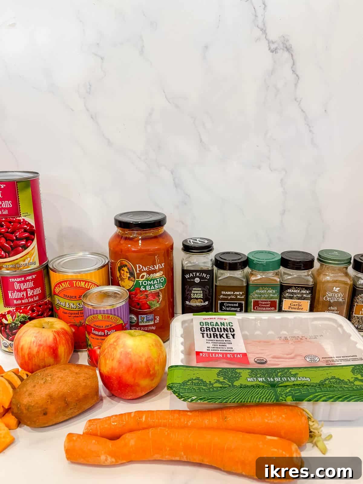 A vibrant selection of ingredients for turkey apple chili, including diced apples, carrots, sweet potatoes, ground turkey, and various spices.