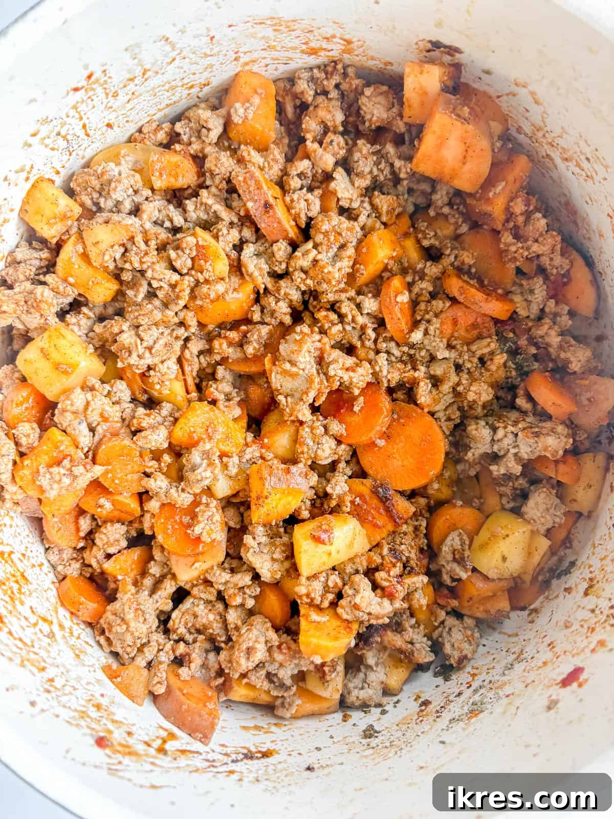 Tomato paste being stirred into the browned ground turkey mixture.