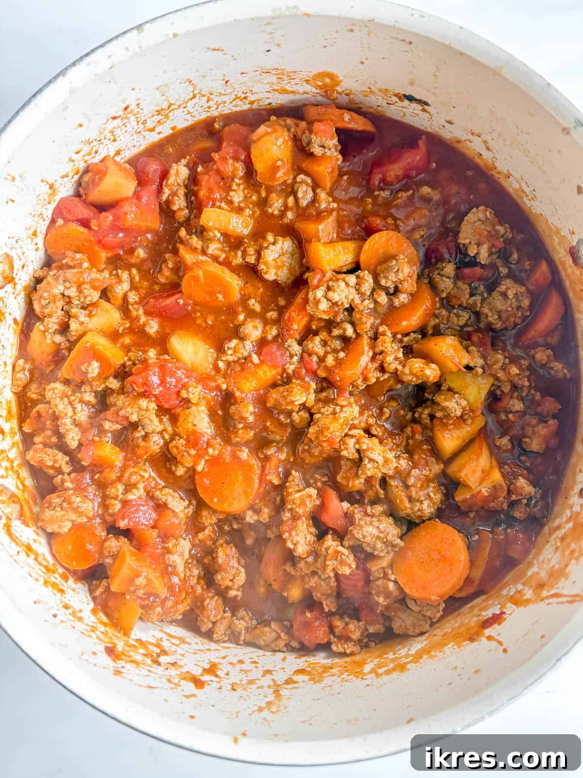 Crushed and strained tomatoes being added to the chili pot.