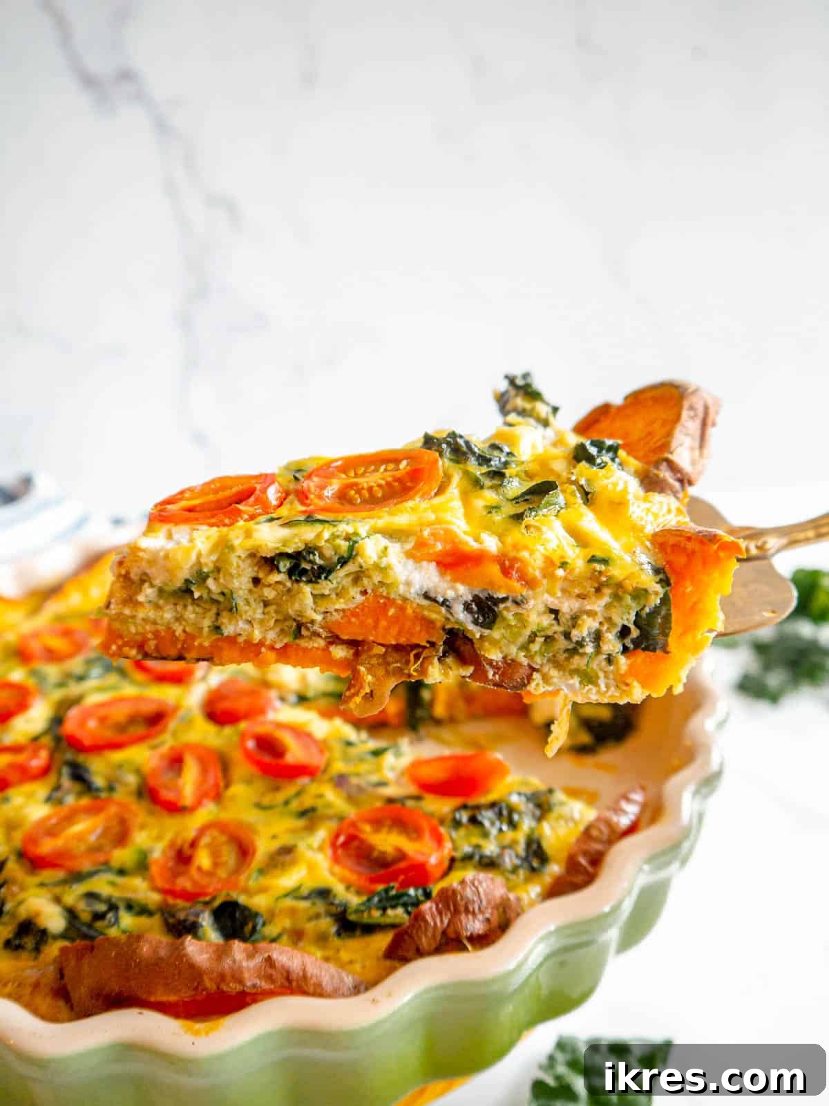 A perfectly sliced piece of sweet potato and zucchini quiche, revealing its vibrant, veggie-filled interior and golden crust.