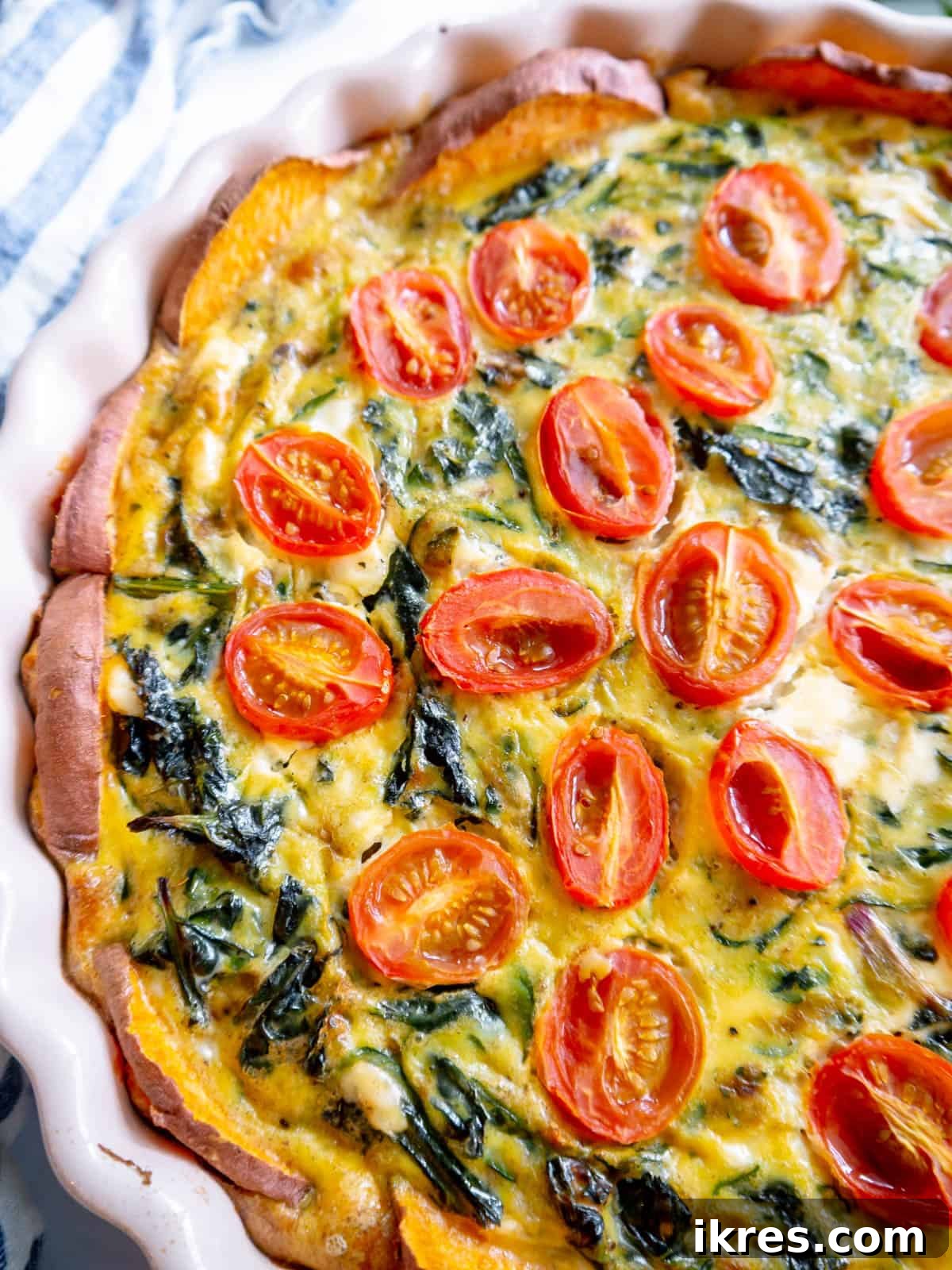 A vibrant, close-up shot of the finished quiche, highlighting the fresh kale, zucchini, and cherry tomatoes set against the golden sweet potato crust.