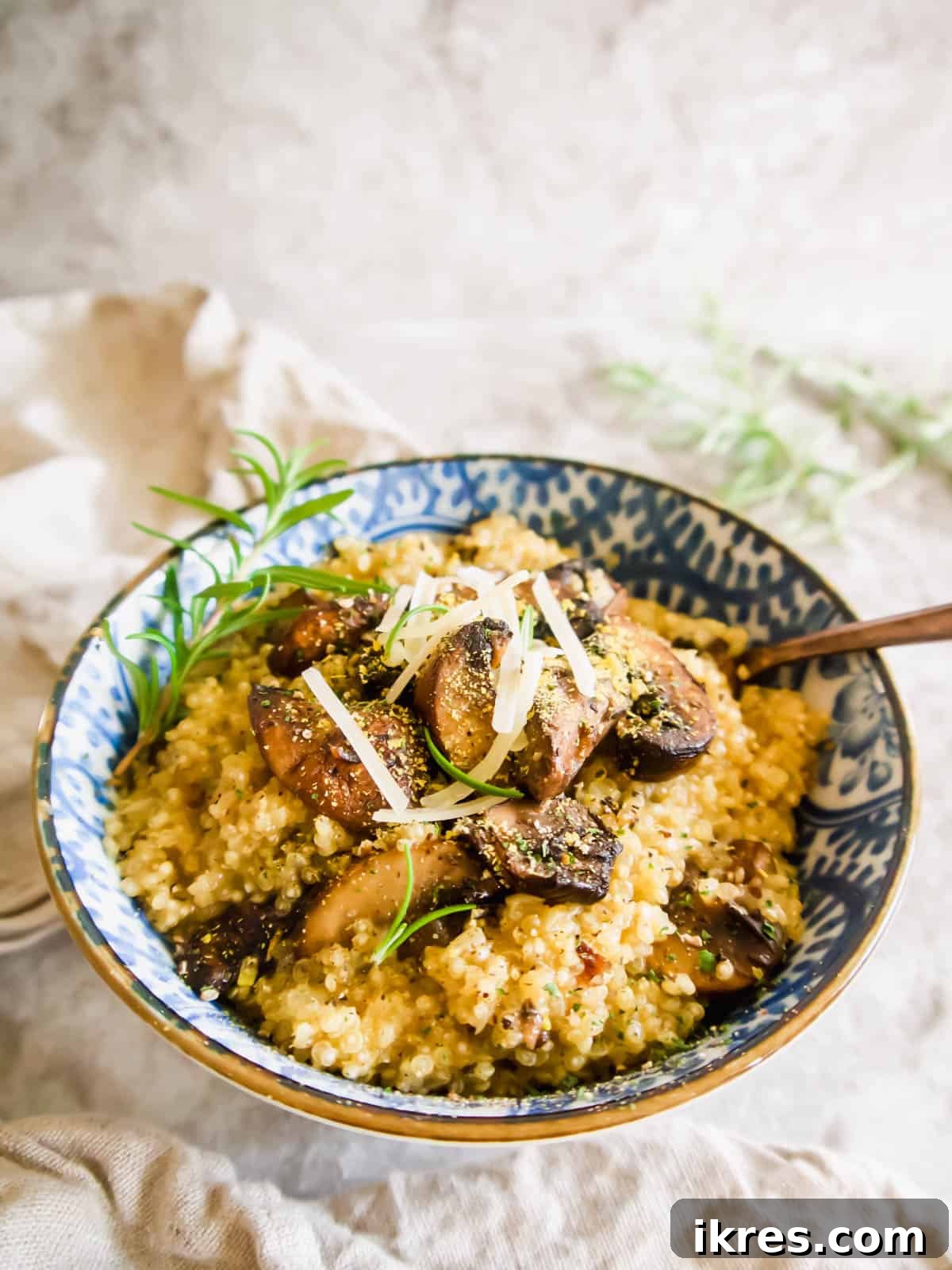A beautifully presented bowl of creamy mushroom quinoa risotto, garnished with fresh Parmesan cheese.
