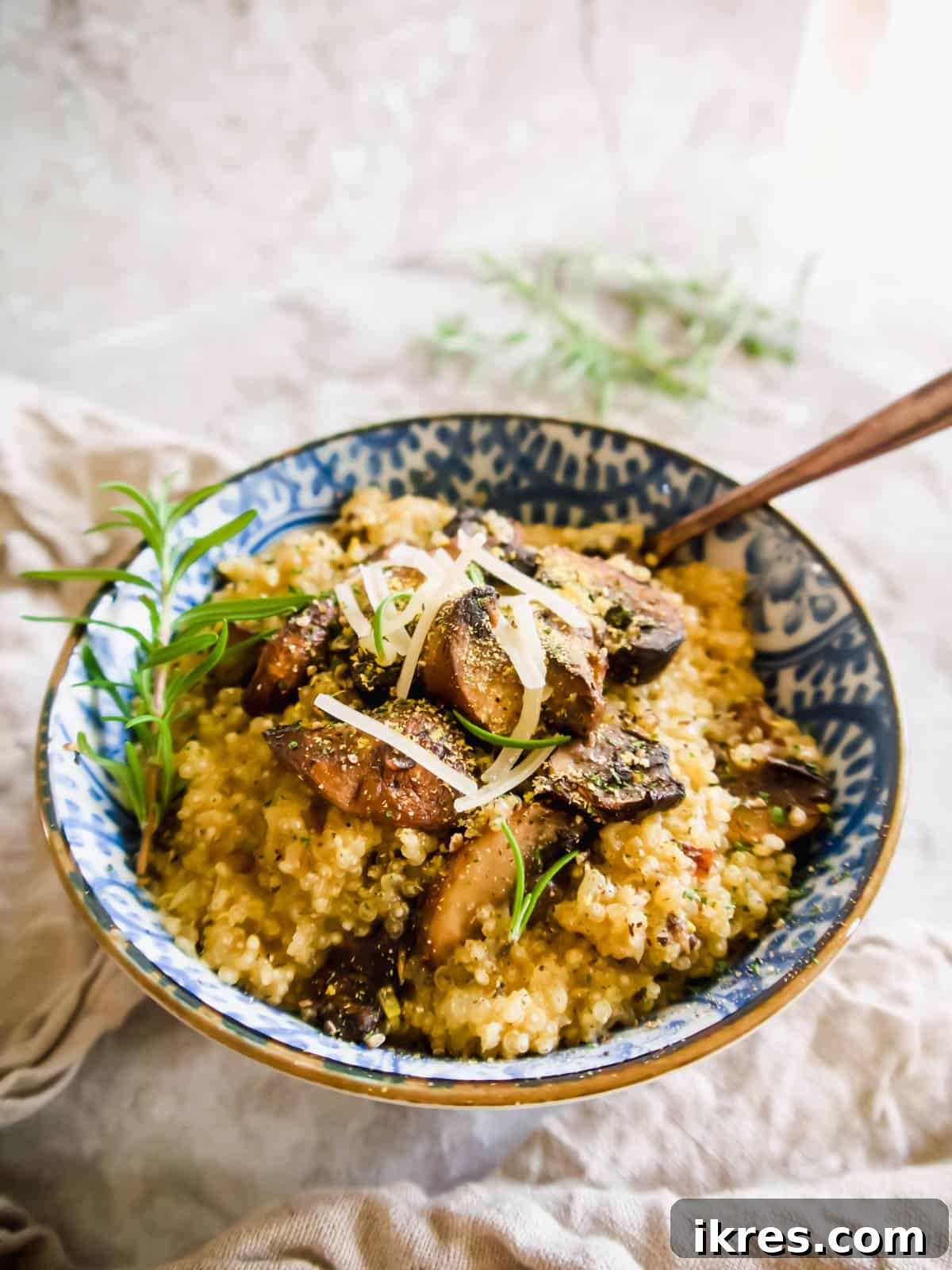 A serving of mushroom quinoa risotto in a bowl with a spoon, highlighting its creamy texture.