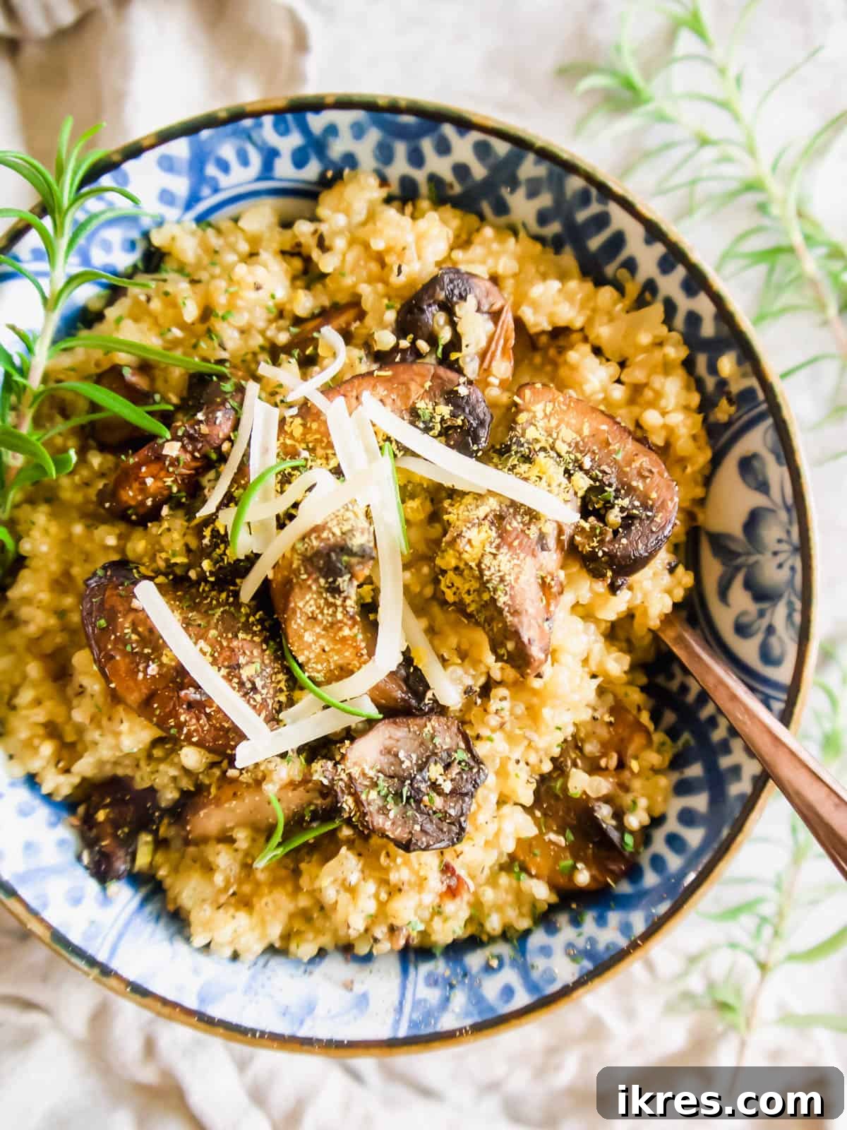 An aerial shot of creamy quinoa risotto, generously topped with sautéed mushrooms and shredded Parmesan, ready to be served.