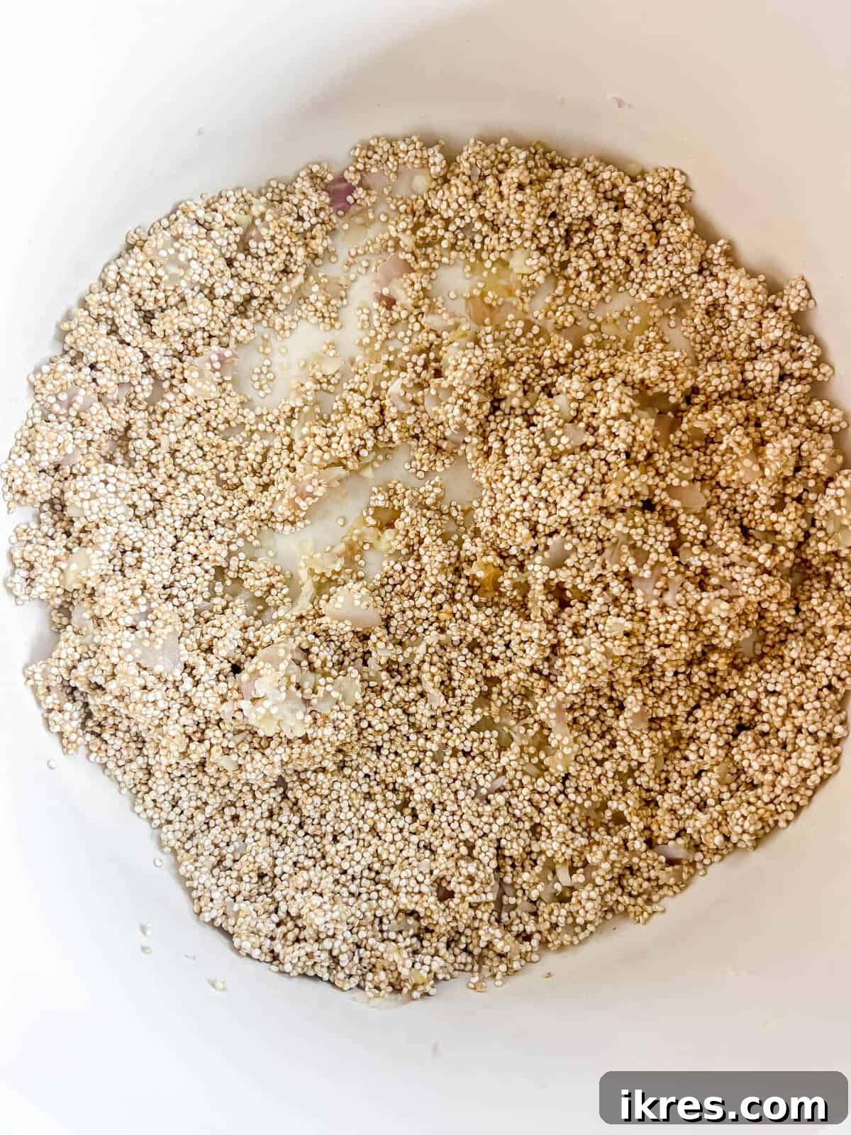 Milk being poured into the pan of quinoa, shallots, and garlic.