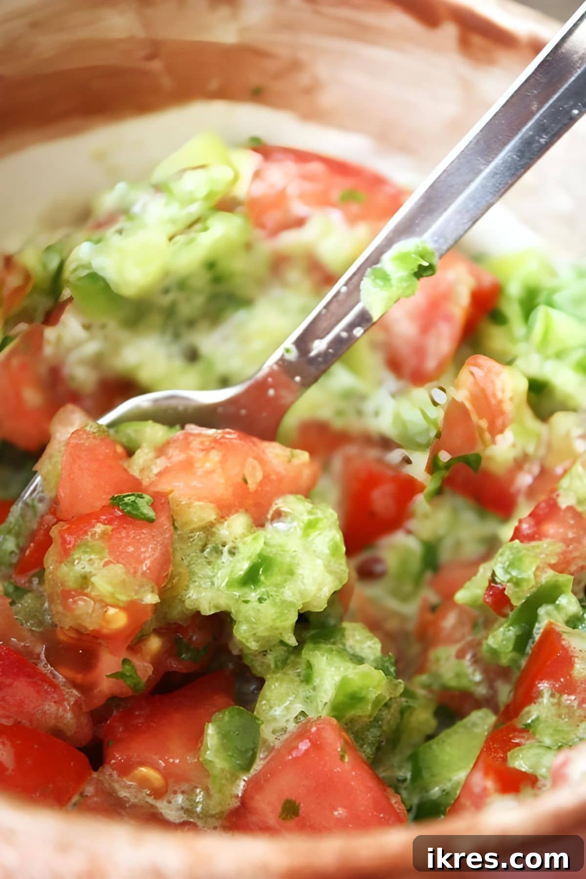 Bright & Bold Pico de Gallo: Fresh Cilantro & Tomato Salsa 4 A spoon mixing up fresh salsa in a bowl, showing vibrant colors of tomatoes, peppers, and cilantro for a perfect blend