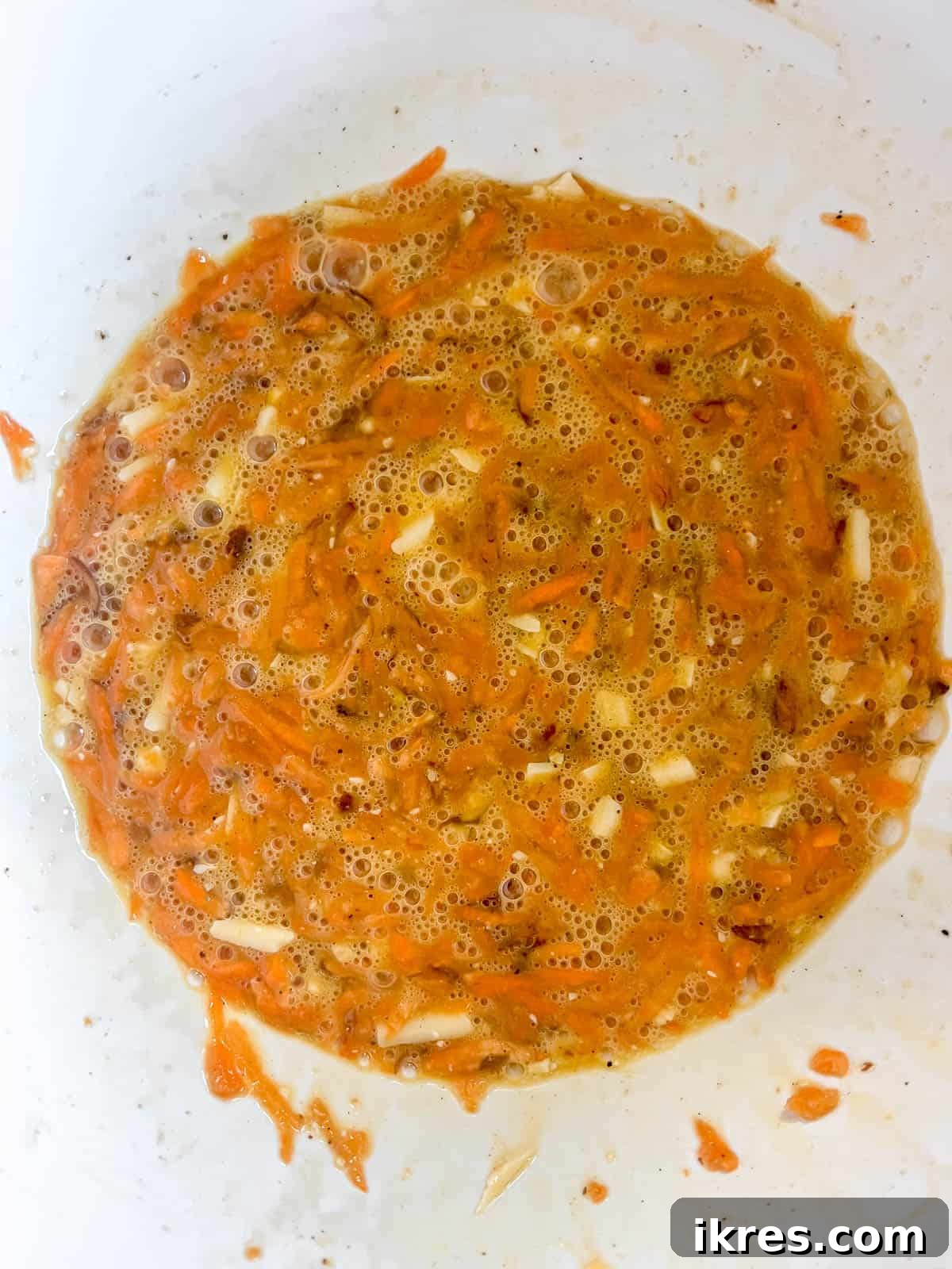 The vibrant shredded sweet potato and rich shredded cheese added to the whisked egg mixture, ready for gentle folding.