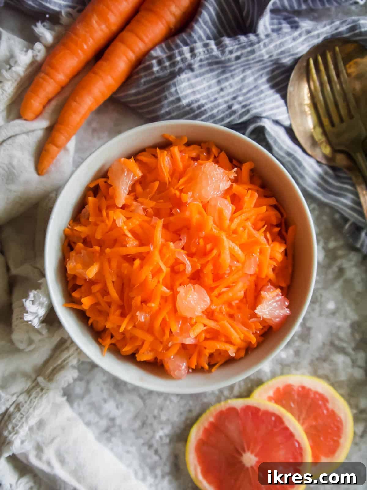 Sunshine Carrot Grapefruit Salad 3 Close-up aerial view of freshly shredded raw carrots in a bowl, highlighting their vibrant orange color and texture.