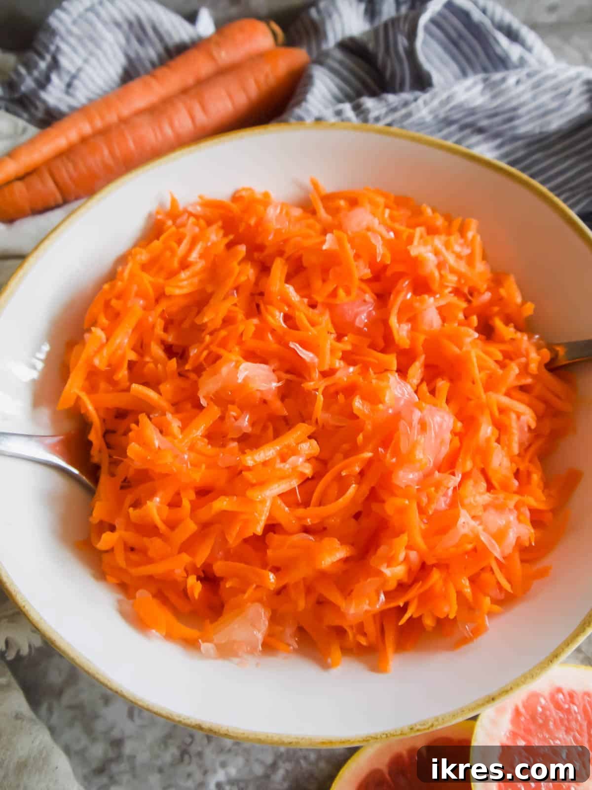 Sunshine Carrot Grapefruit Salad 5 A large serving bowl filled with the vibrant Raw Carrot Grapefruit Salad, garnished and ready for sharing, with serving spoons nestled within.