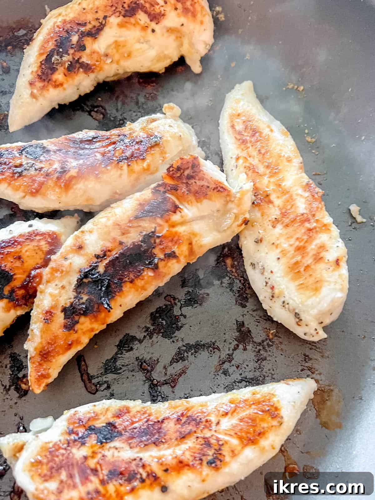 Power-Packed Kale Cobb Salad 8 Boneless chicken breast cooking in a frying pan over medium heat, seasoned with garlic, onion, salt, pepper, and lemon juice until golden brown.
