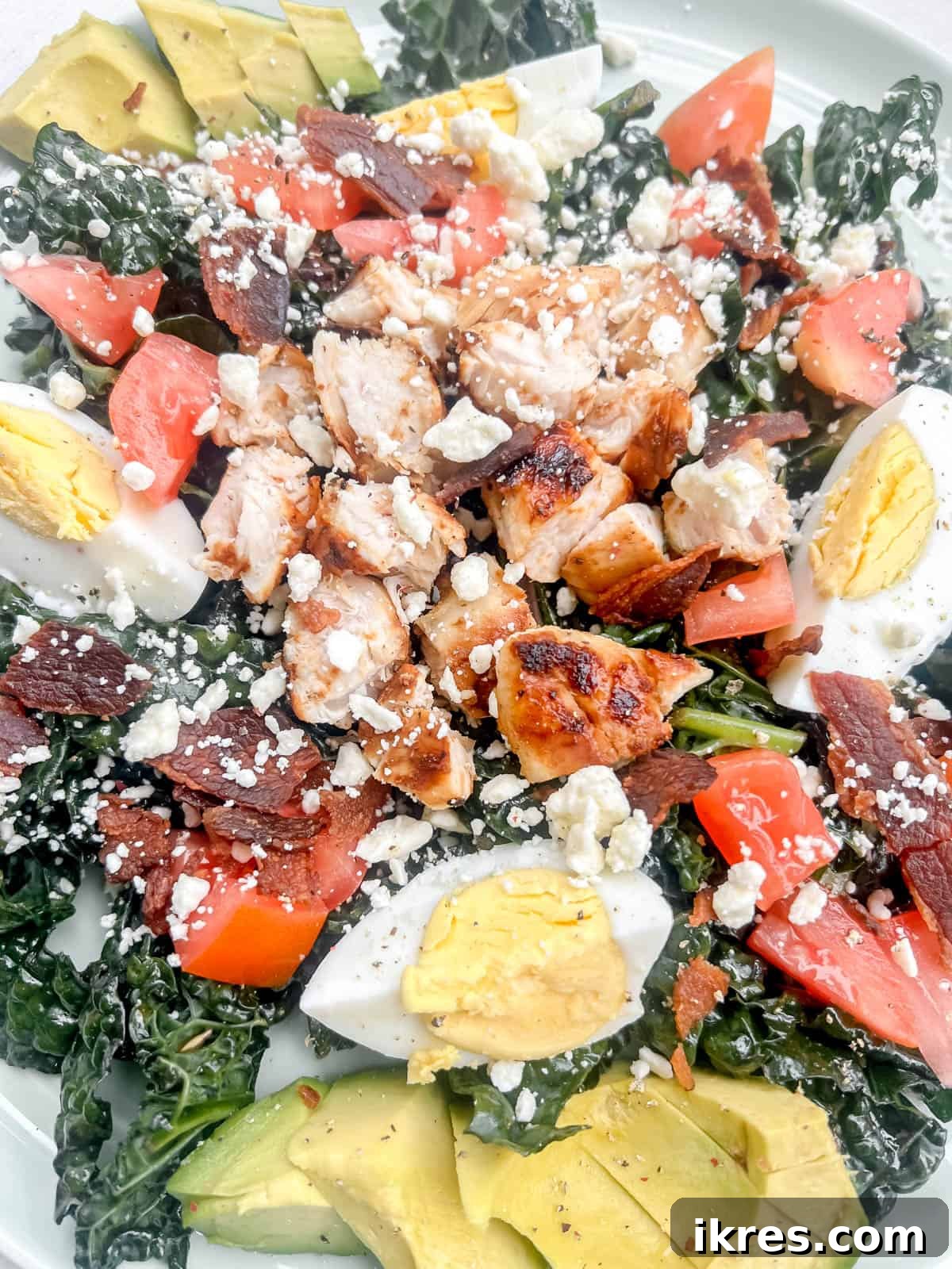 Power-Packed Kale Cobb Salad 10 A fully assembled healthy cobb salad recipe on a dinner plate, showcasing all the vibrant ingredients neatly arranged.