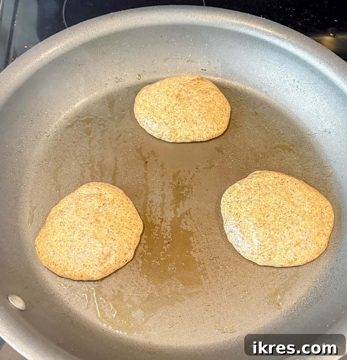Several mini chia-flax protein pancakes cooking on a greased pan over medium heat, showing the bubbling process.