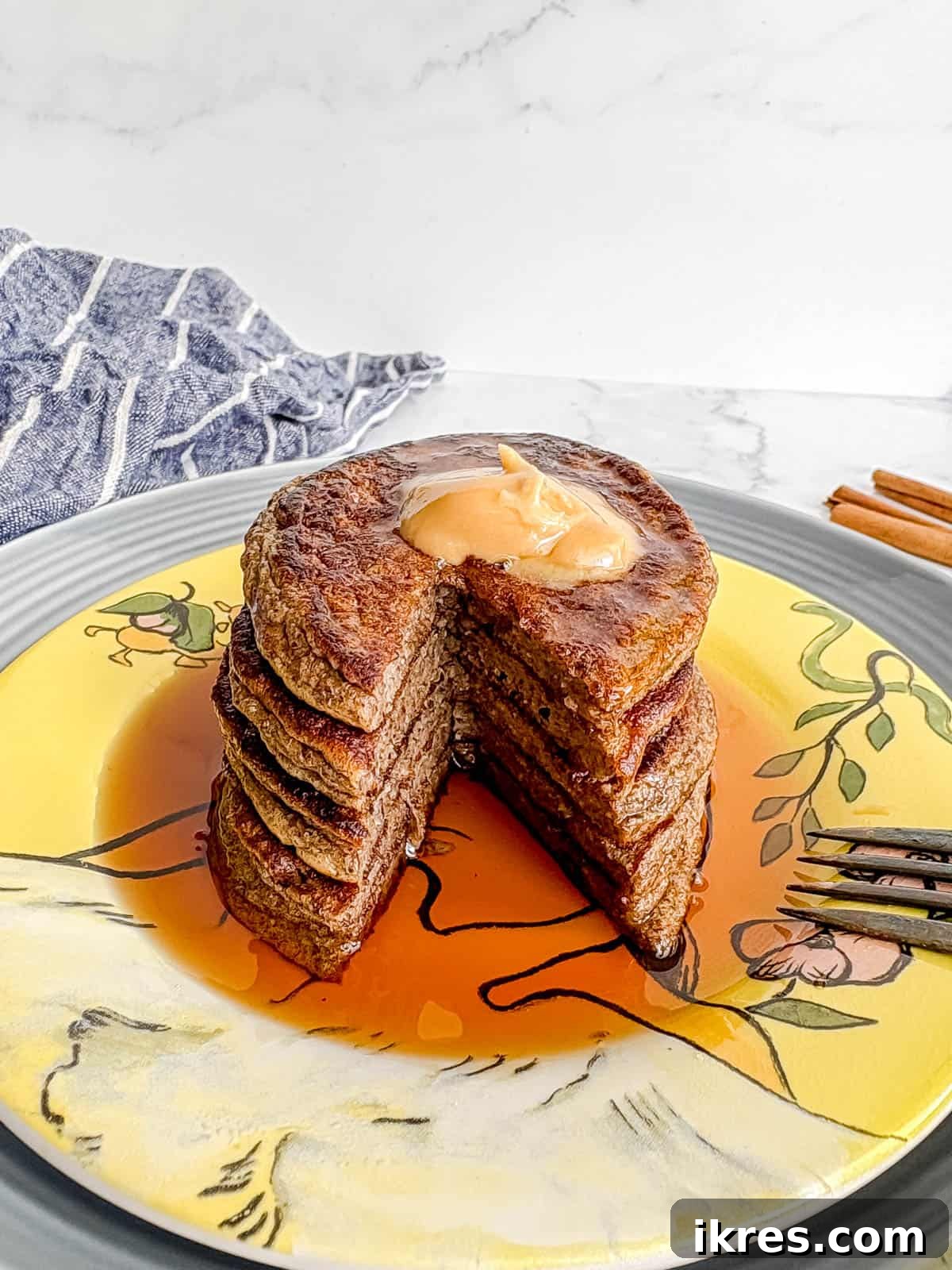 A close-up shot of a stack of fluffy chia flax protein pancakes, with one pancake cut open to reveal its moist and textured interior.