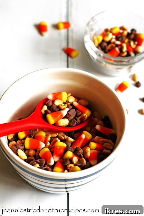 Sweet & Salalty Candy Corn Crunch 2 Candy Corn Mix in a white bowl with a large red spoon, surrounded by smaller clear dishes containing the mix.