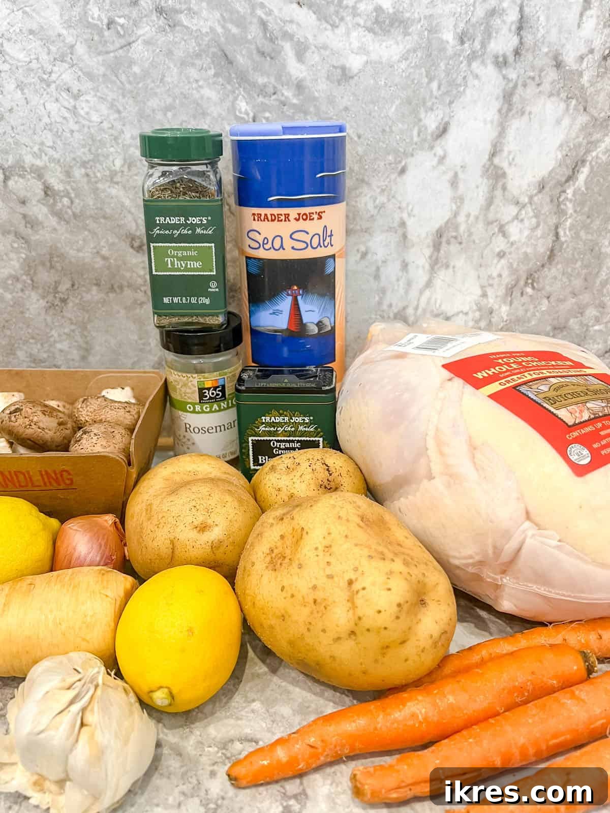 Fresh ingredients laid out: a whole chicken, lemons, thyme, rosemary, garlic, onions, parsnips, mushrooms, and carrots.