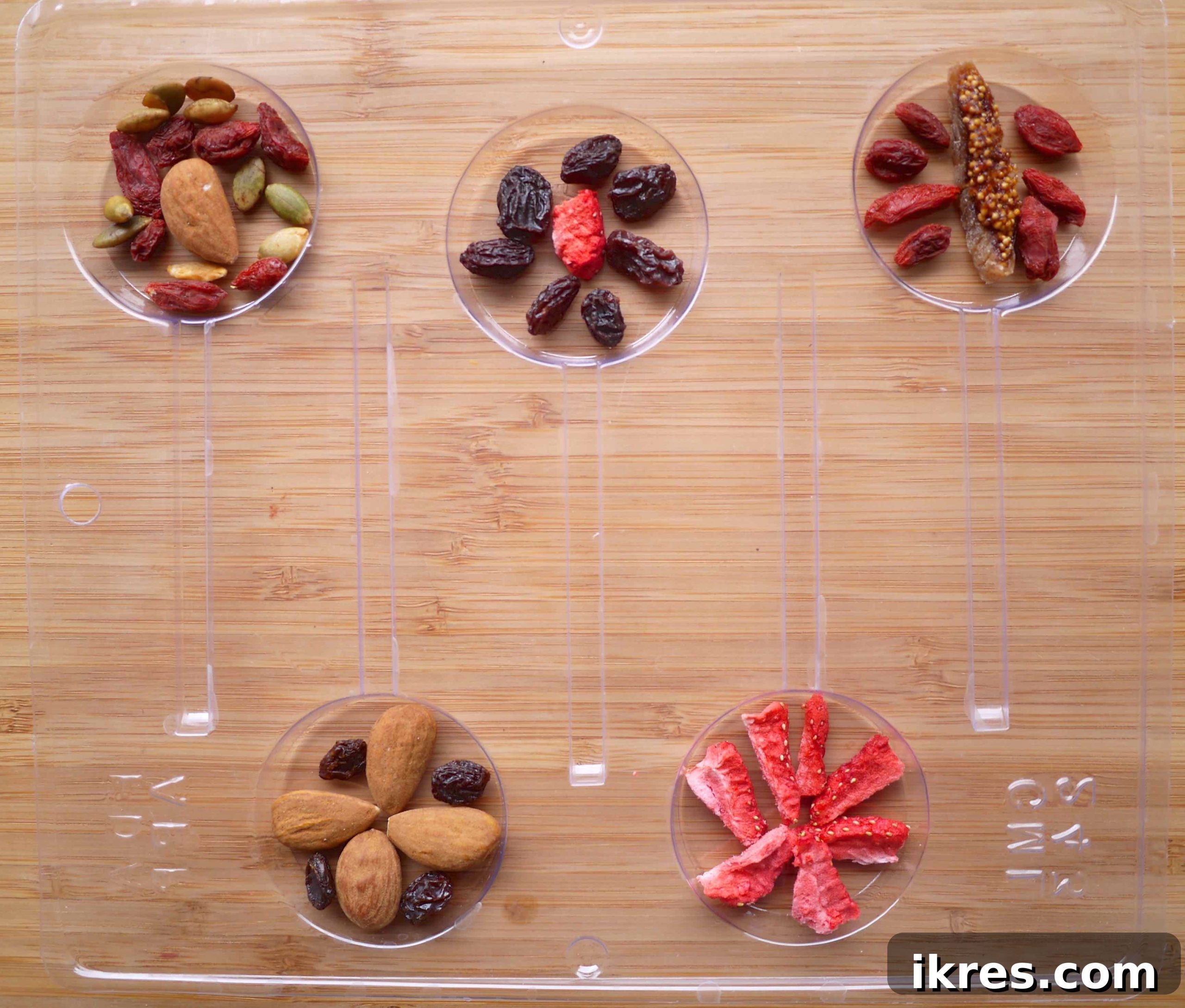 Carefully arranging dried fruit and nuts into the individual sections of a chocolate lollipop mold.