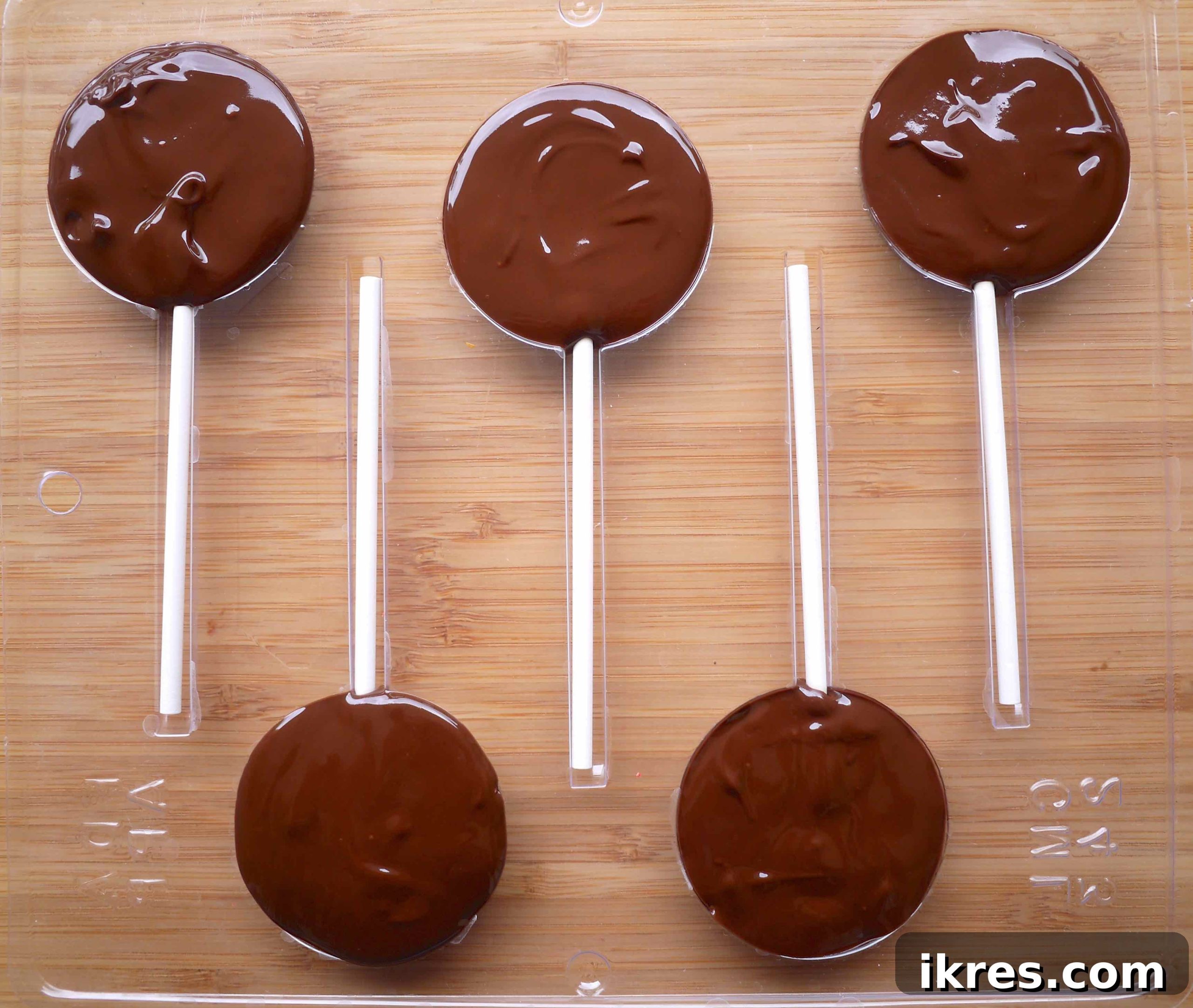 Ensuring all molds are completely filled with melted chocolate, covering all elements.