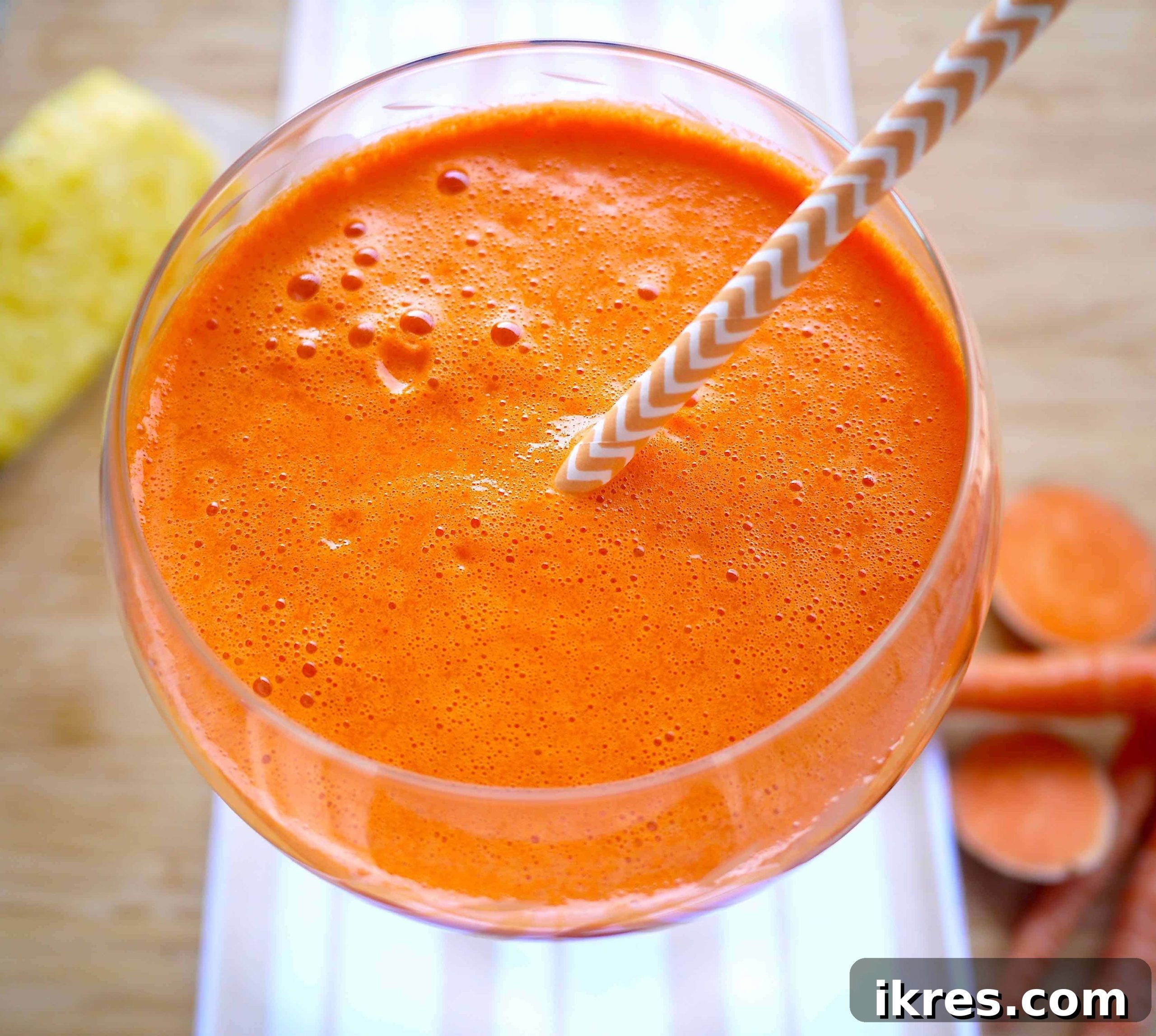A vibrant glass of fresh sweet potato, carrot, mango, and pineapple juice, ready to drink.