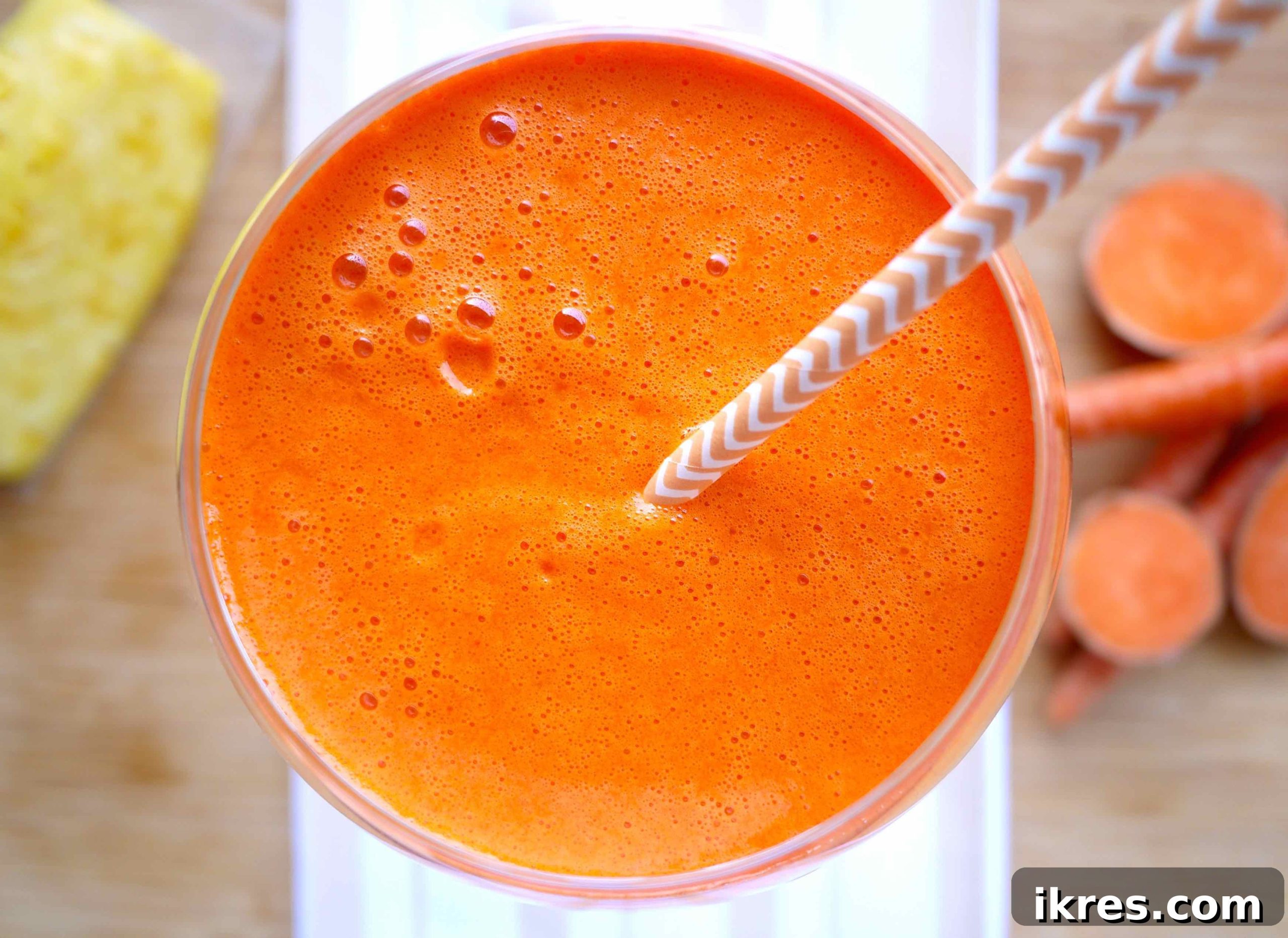 A glass filled with vibrant sweet potato, mango, carrot, and pineapple juice, showcasing its rich orange color.