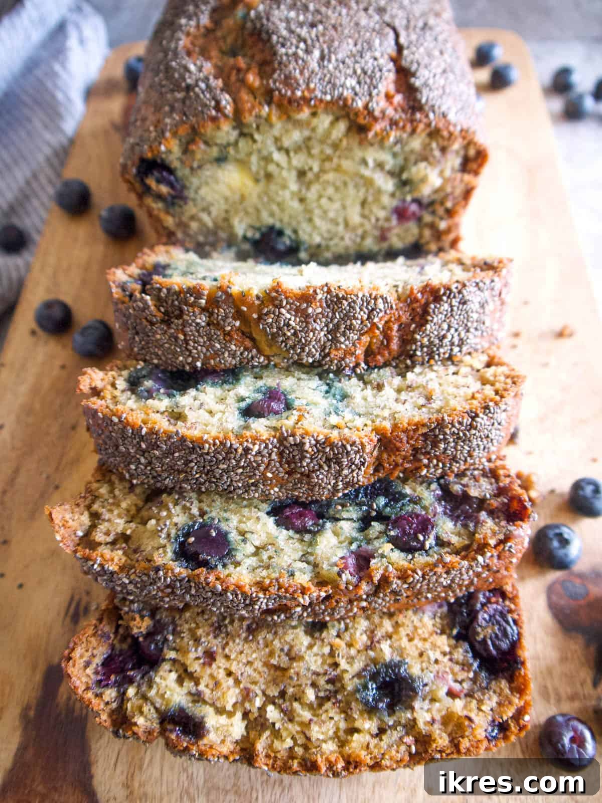Slices of Healthy Blueberry Banana Bread with Chia Seeds on a cutting board, showcasing its moist texture and blueberry distribution.