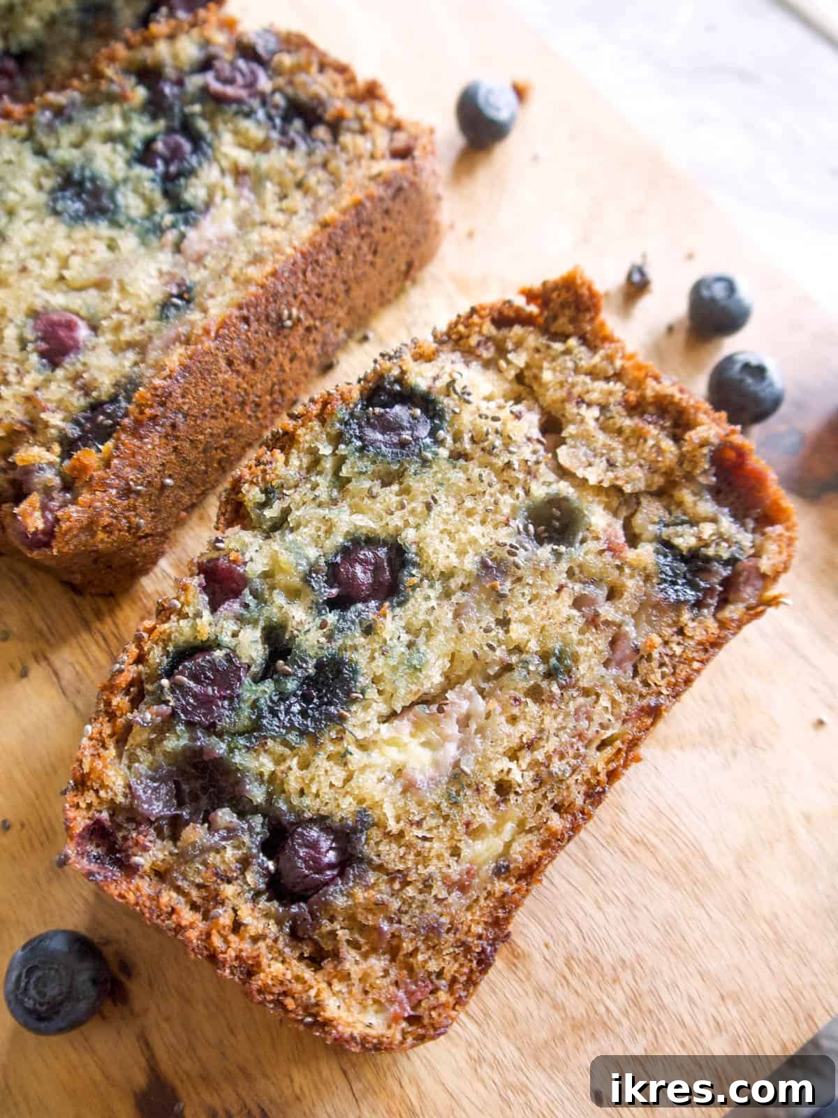 One perfectly sliced piece of healthy banana blueberry bread on a pristine white plate, ready to be savored.