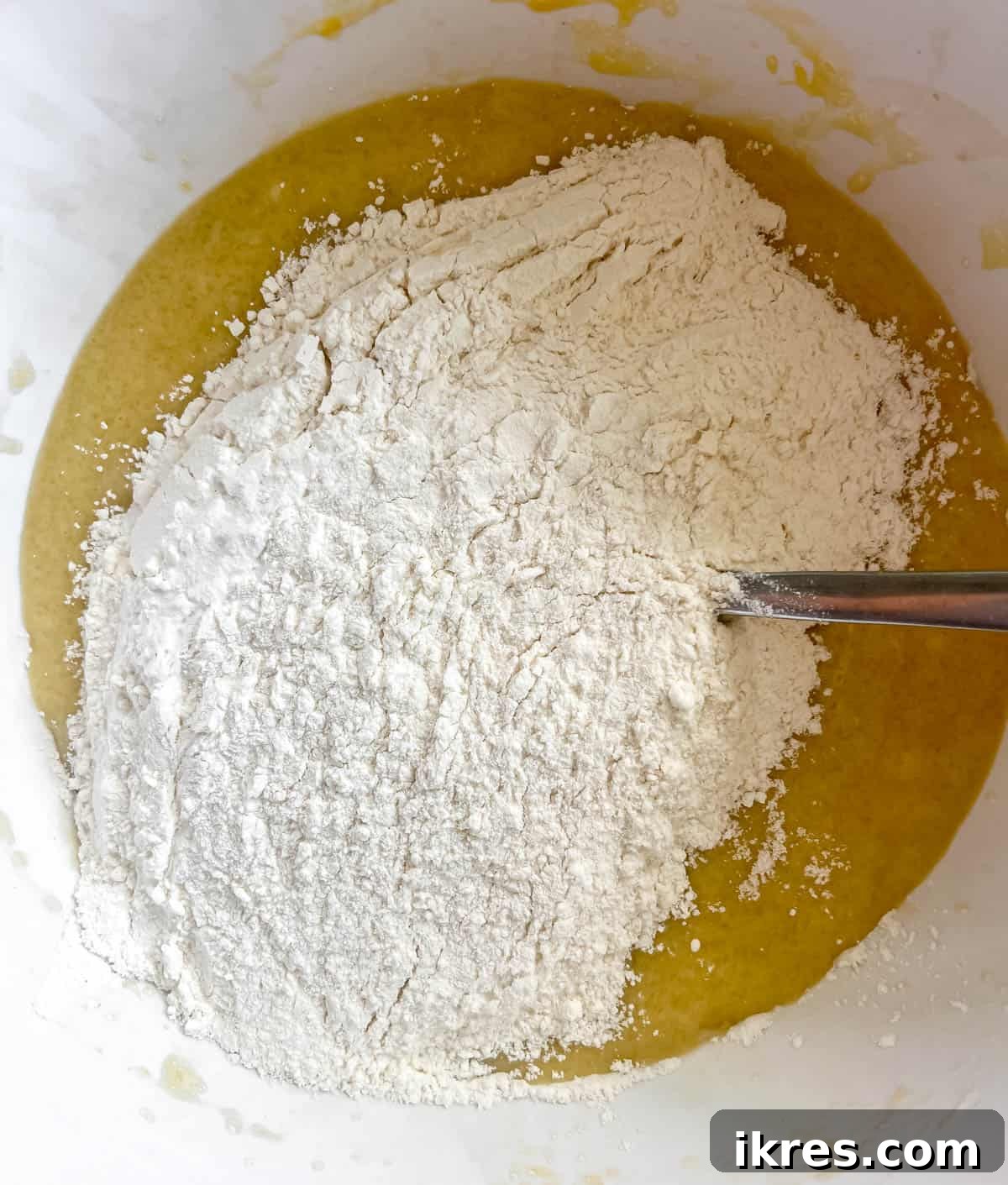 Dry ingredients being poured into the bowl of wet ingredients.