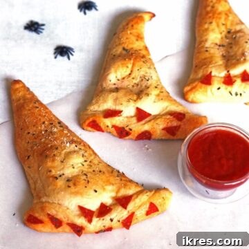 Bewitching Calzone Caps 14 Three Witch Hat Calzones with a small bowl of marinara sauce and some plastic spiders.