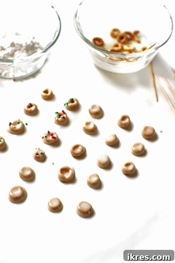 Elven Delights 4 Freshly coated Cheerios, transformed into festive Elf Donuts, are adorned with vibrant red and green sprinkles and left to dry on parchment paper.