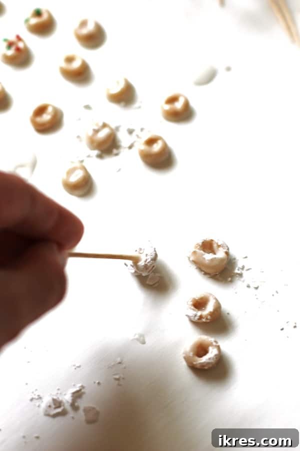 Elven Delights 6 Using a toothpick to carefully pick up and transfer freshly made Elf Donuts to a drying surface, ensuring their perfect shape is preserved.