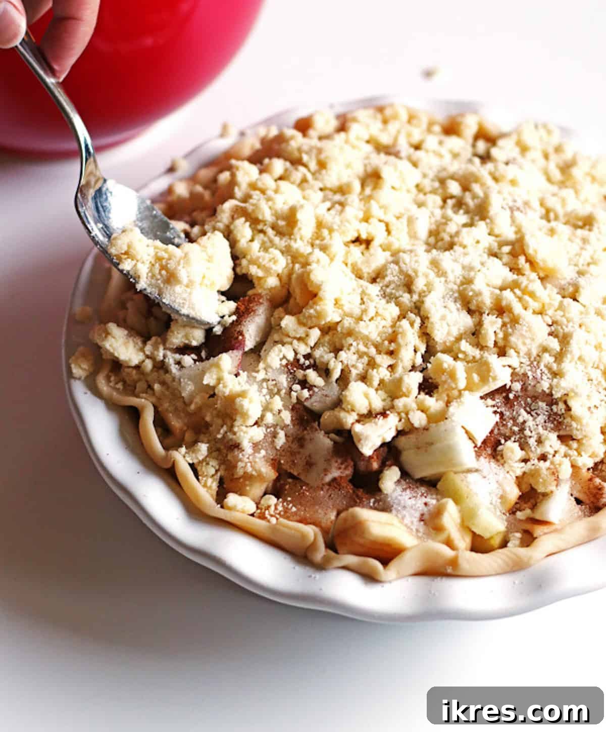 Homestyle Dutch Apple Pie 6 Adding crumb topping to top of the pie using a spoon