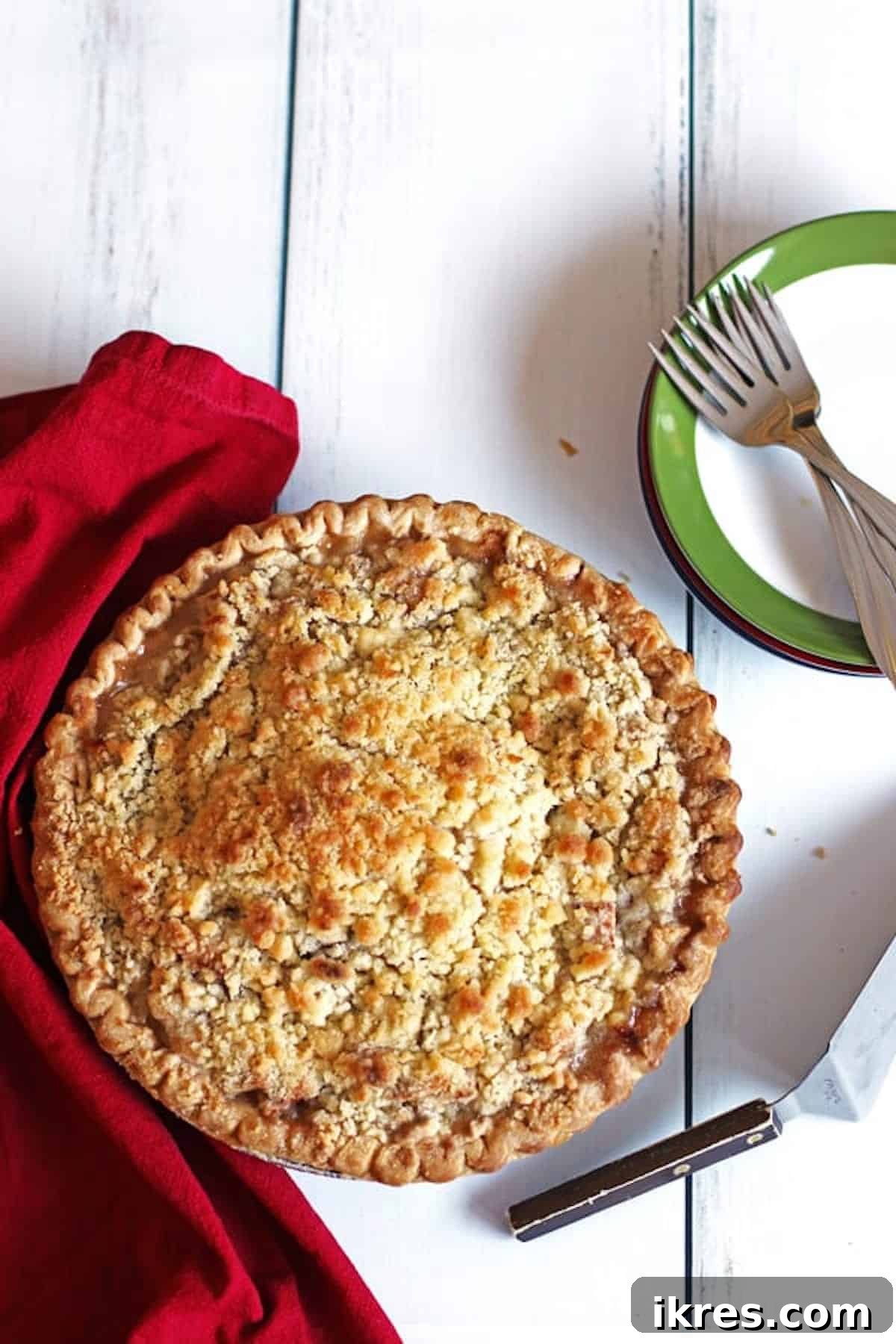 Homestyle Dutch Apple Pie 8 Apple Pie on a white table with plates and forks to the side of it along with a pie server