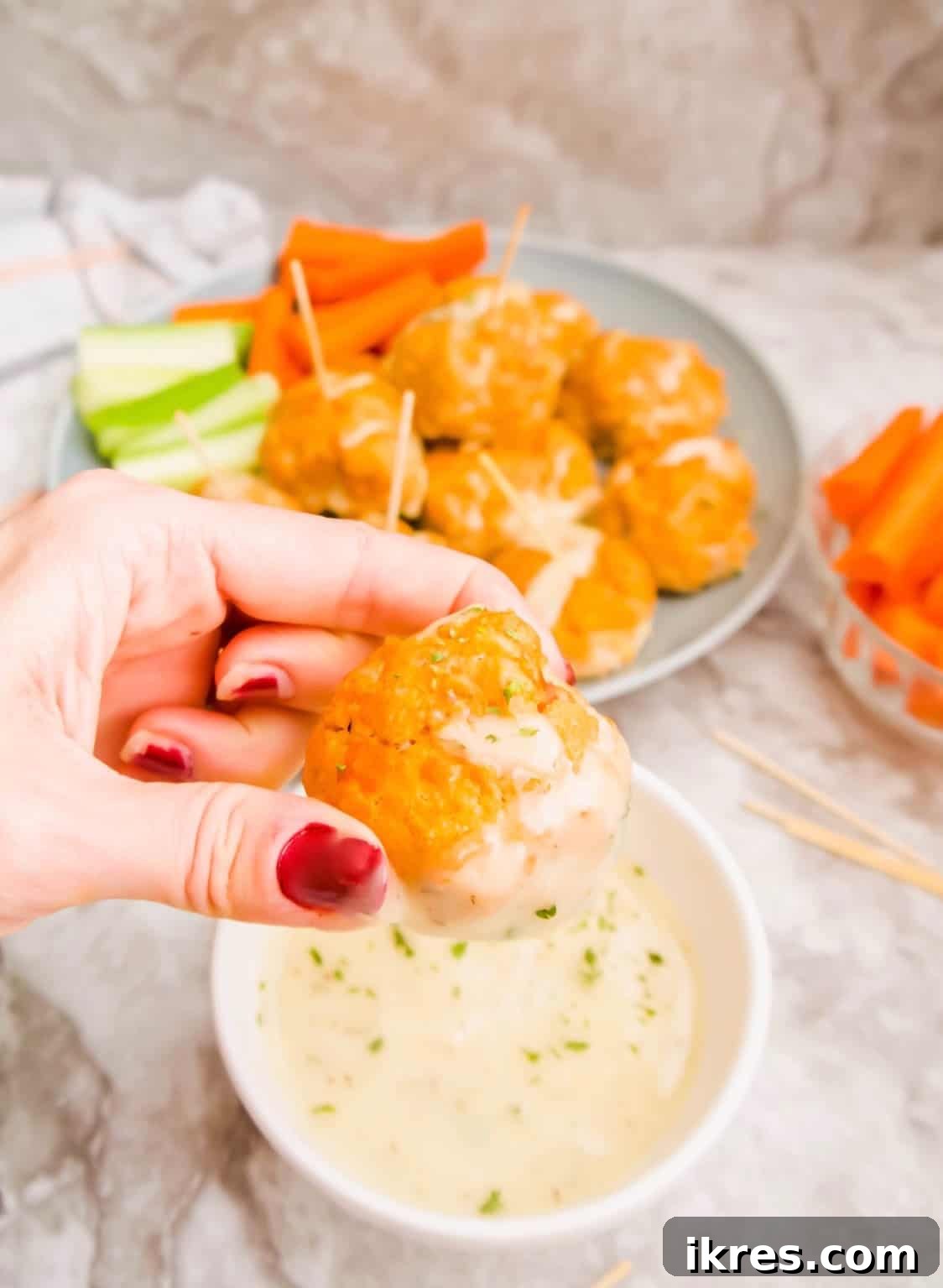 Guilt-Free Buffalo Turkey Meatballs: Your Paleo Whole30 Favorite 9 Dipping a healthy buffalo turkey meatball into a creamy ranch sauce, highlighting its delicious pairing.