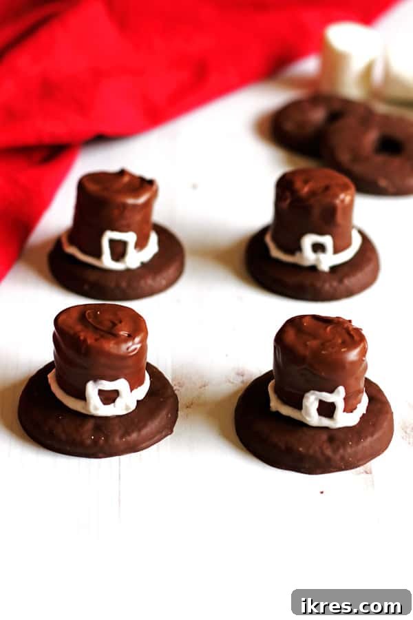 Pilgrim Hat Thanksgiving Treats 7 Finished Pilgrim Hat Cookies, decorated with white frosting buckles, arranged on a white table, perfectly capturing the Thanksgiving theme.