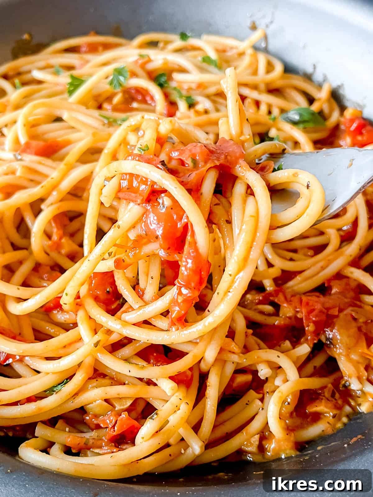 Bursting Cherry Tomato Garlic Sauce 2 Freshly made cherry tomato sauce with garlic, generously coating a bed of spaghetti.