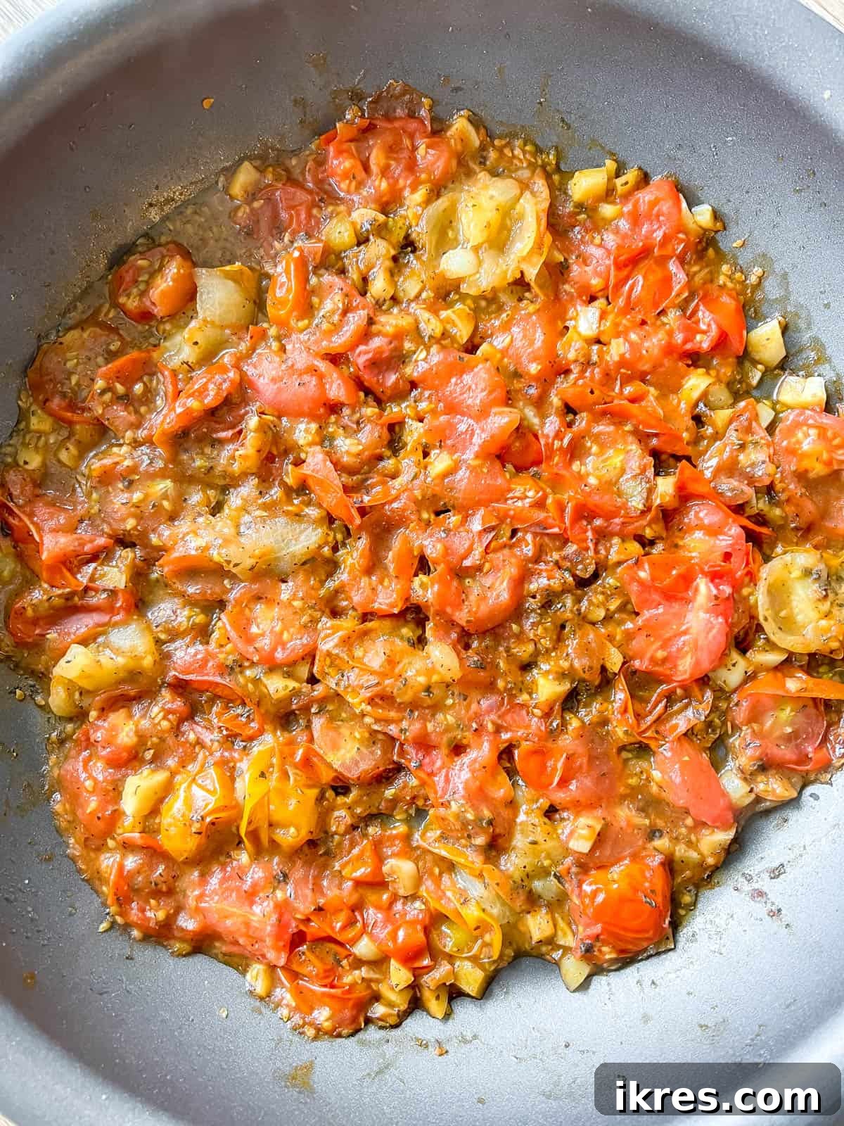 Bursting Cherry Tomato Garlic Sauce 5 Halved cherry tomatoes, red chili flakes, salt, pepper, dried oregano, and dried basil being added to the sautéed garlic in a pan.