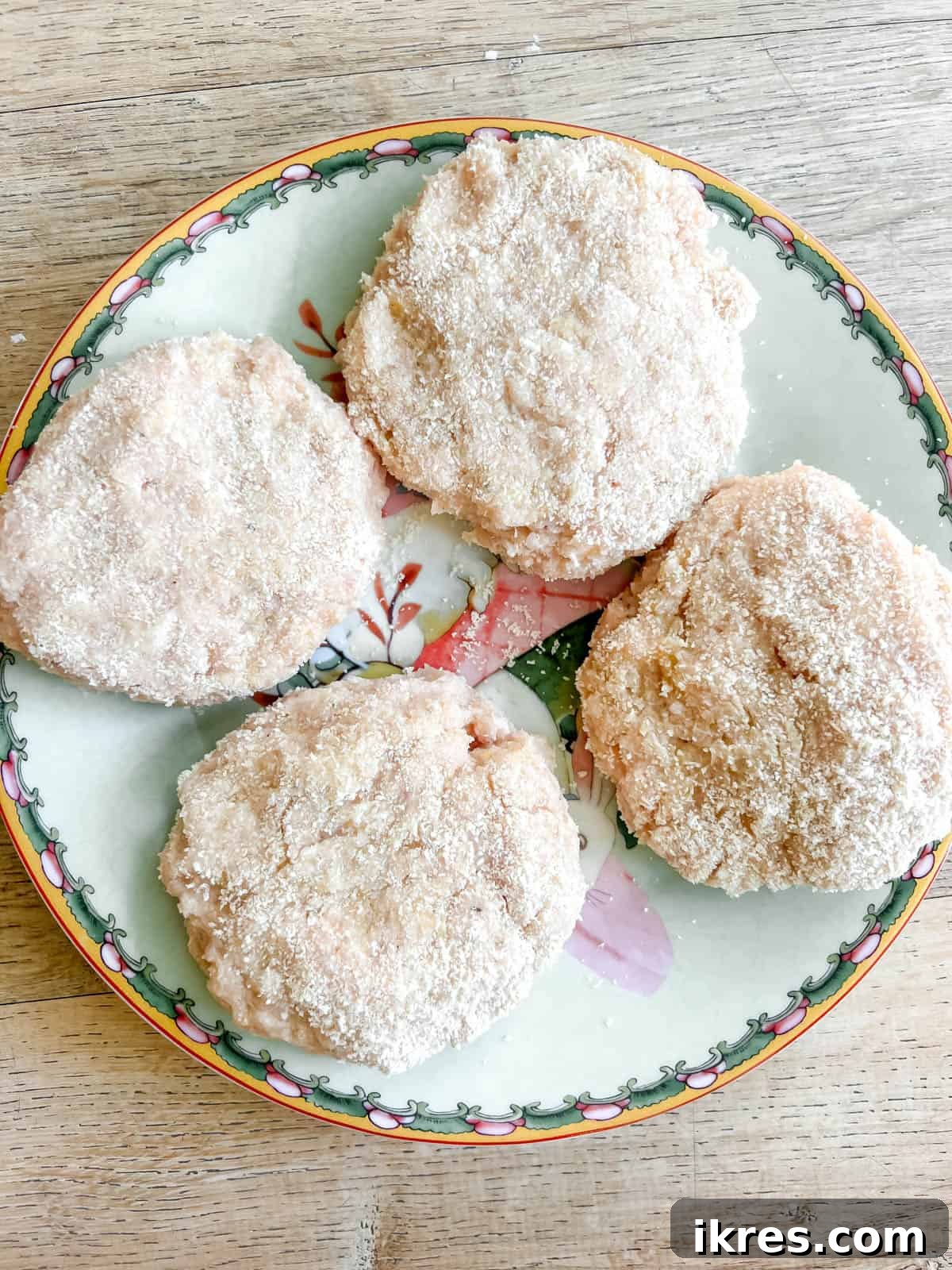 Uncooked chicken burgers placed neatly on a plate, ready for cooking.