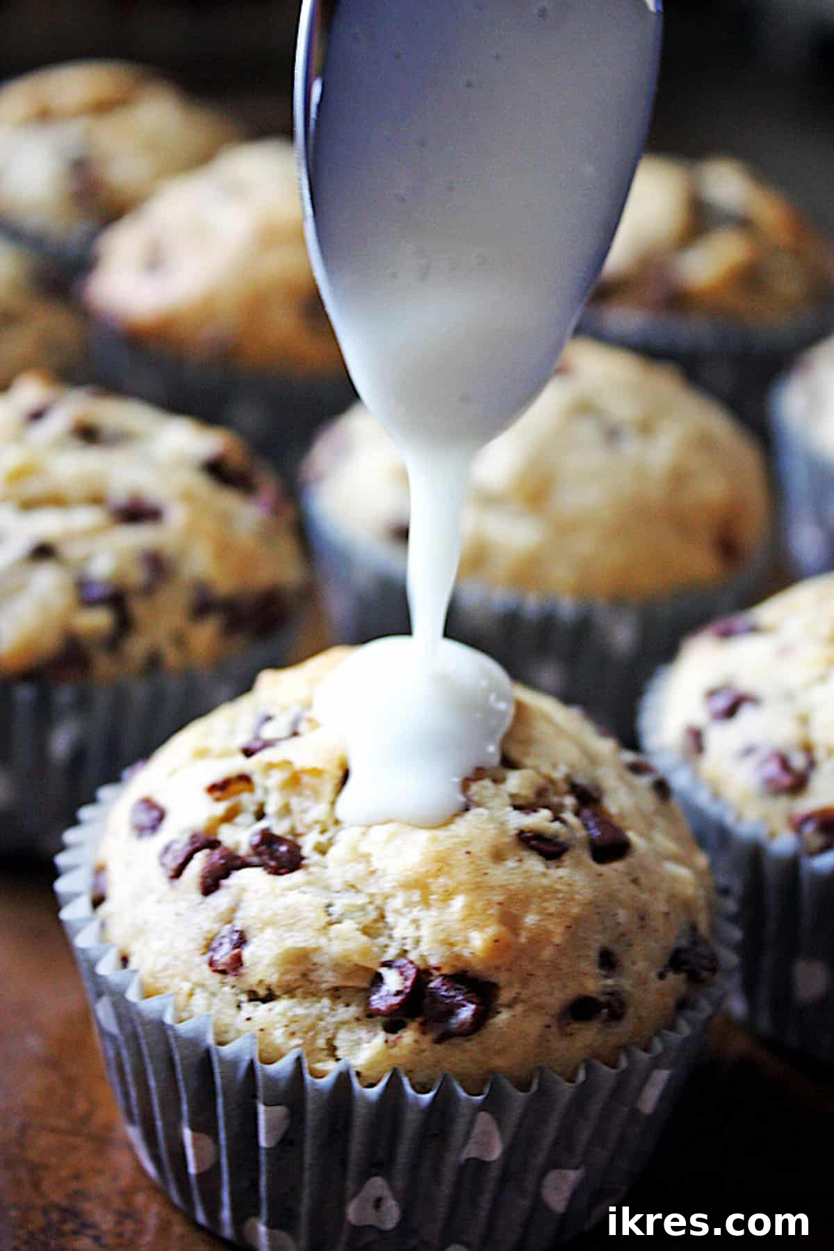 Glazed banana nut chocolate chip muffins cooling on a wire rack.
