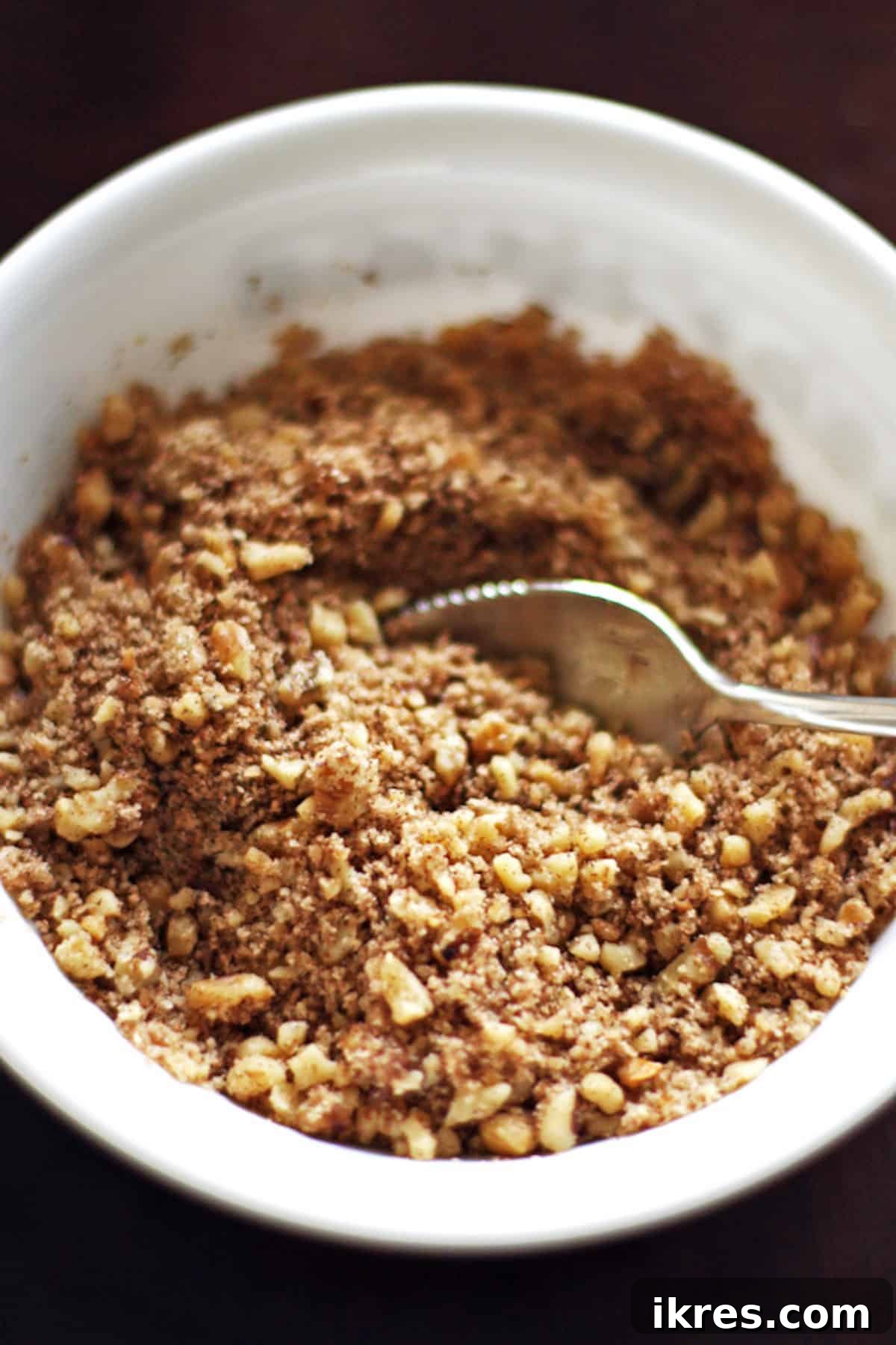 A small bowl of streusel crumble made with brown sugar, walnuts, and cinnamon, ready for layering.