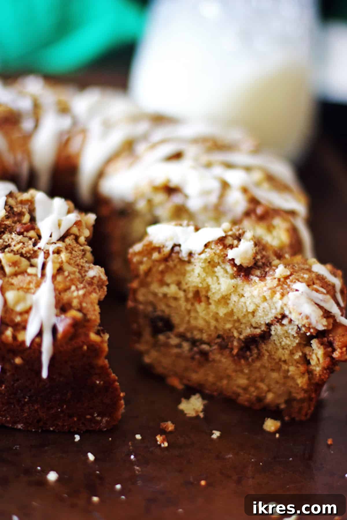 A perfect slice of cinnamon streusel coffee cake resting on the main cake, showcasing its layered interior and glaze.