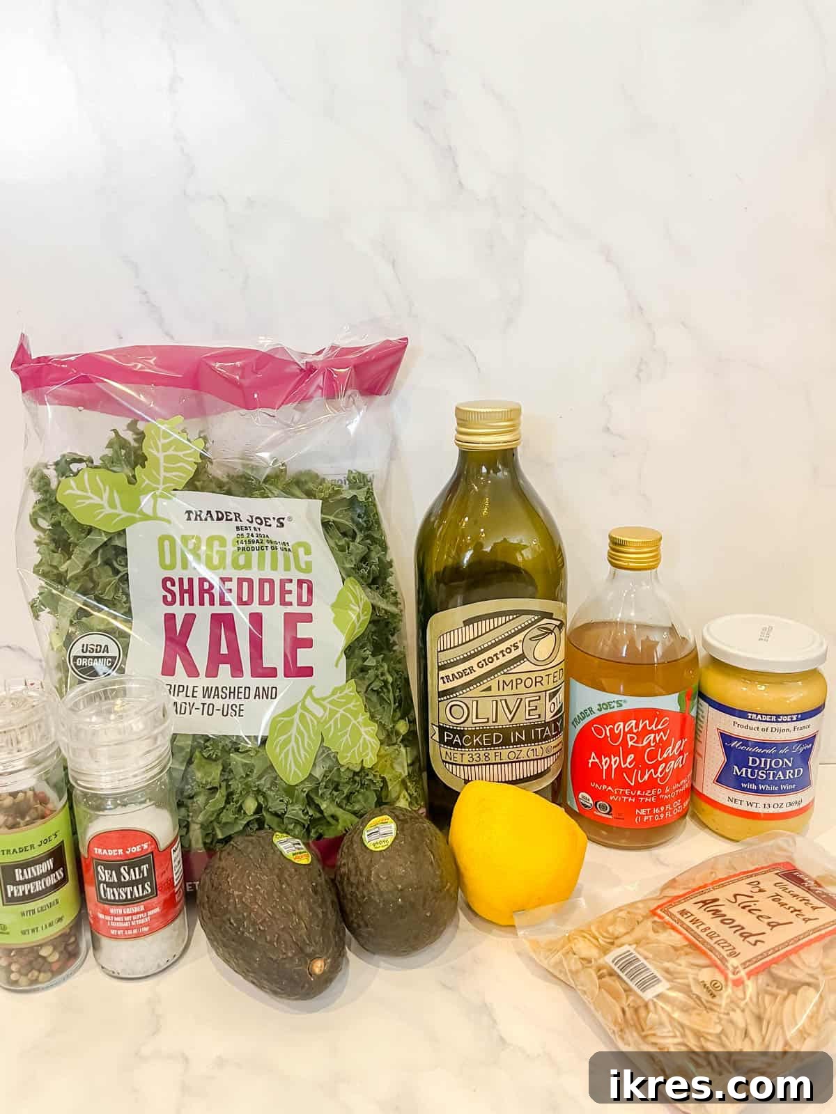 Lemon-Kissed Kale Avocado Salad 3 A selection of fresh, high-quality ingredients including kale, avocado, almonds, raisins, olive oil, lemon, apple cider vinegar, and Dijon mustard, ready for salad preparation.