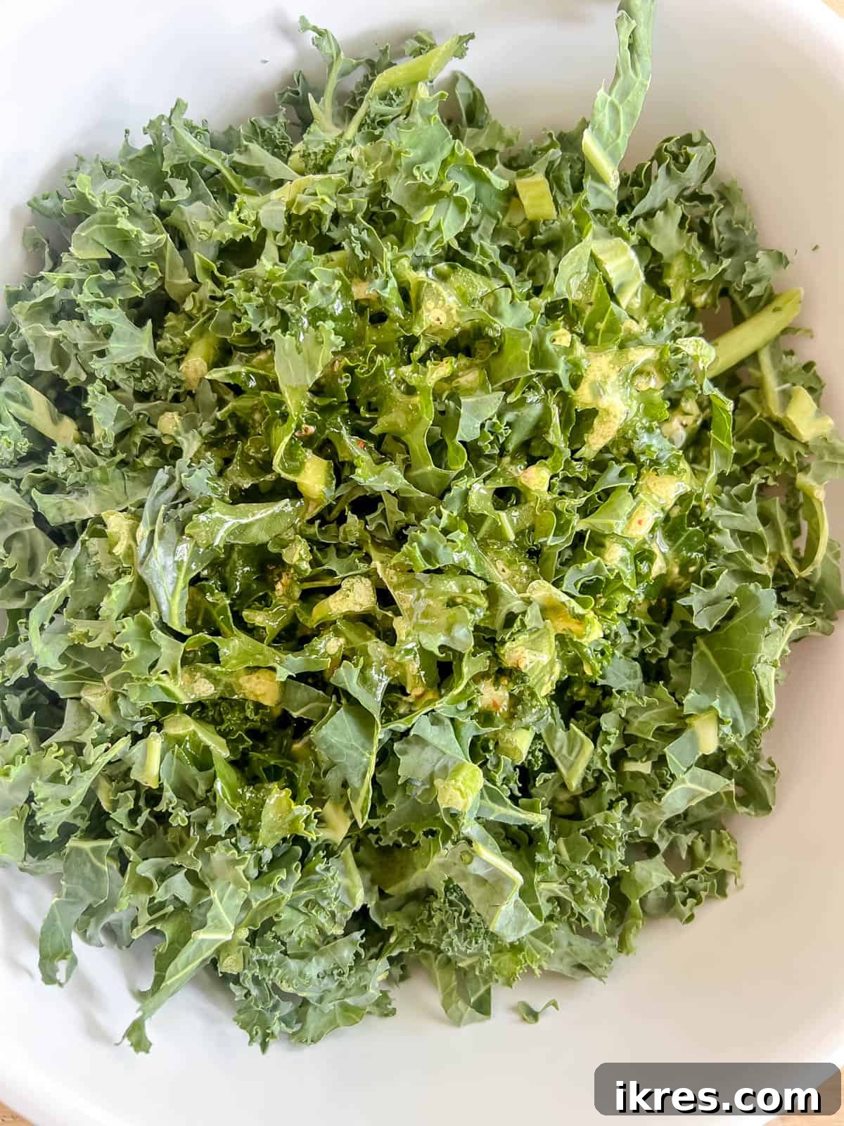 Lemon-Kissed Kale Avocado Salad 5 Finely chopped kale leaves in a large mixing bowl with the freshly prepared lemon dressing being poured over them.