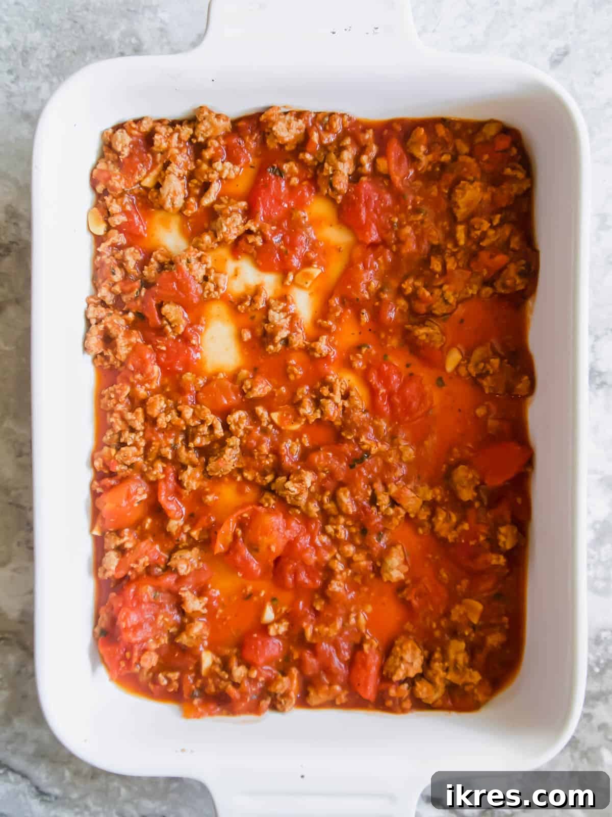 Hearty Turkey and Summer Vegetable Bake 5 A layer of rich ground turkey meat sauce spread evenly in a large baking pan, forming the base of the casserole.