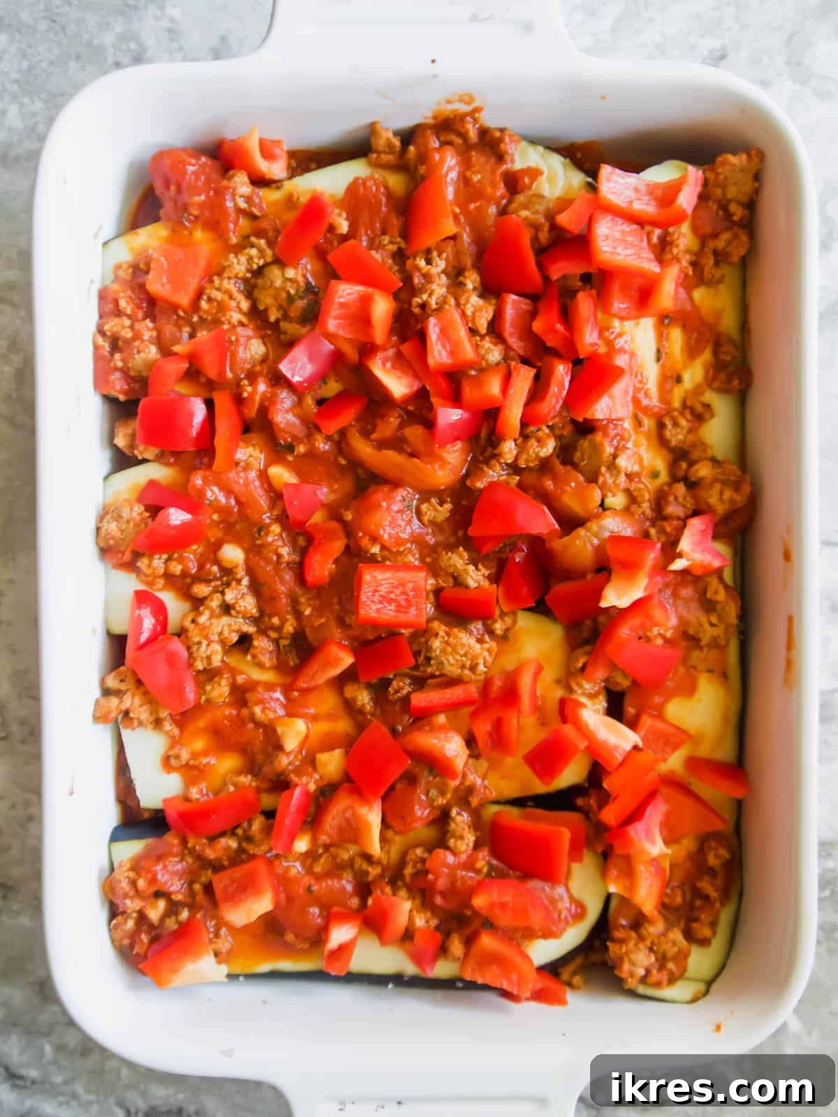 Hearty Turkey and Summer Vegetable Bake 7 Alternating layers of meat sauce and vibrant red bell pepper slices in the casserole dish.