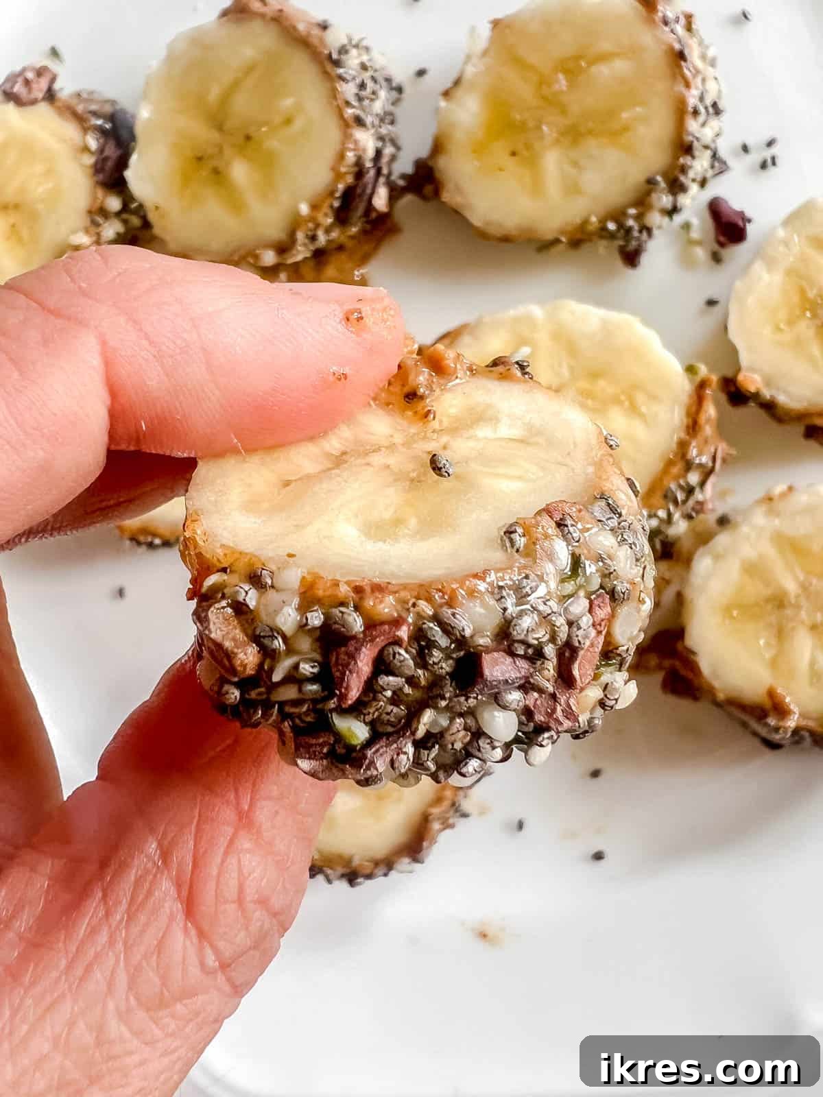 Banana Breakfast Pinwheels 6 A hand holding a single, perfectly sliced piece of breakfast banana sushi, showcasing its appealing layers.
