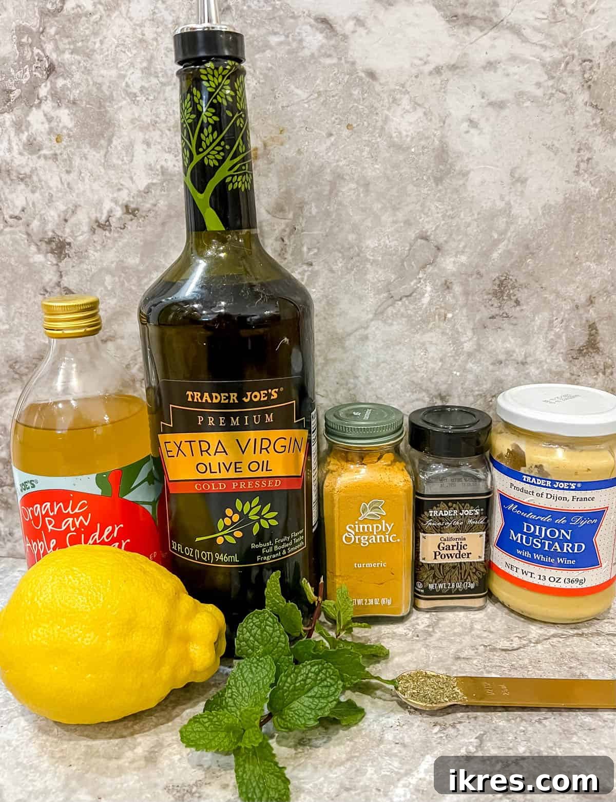 Individual ingredients laid out for making lemon turmeric mint dressing, including lemons, fresh mint, olive oil, and spices.