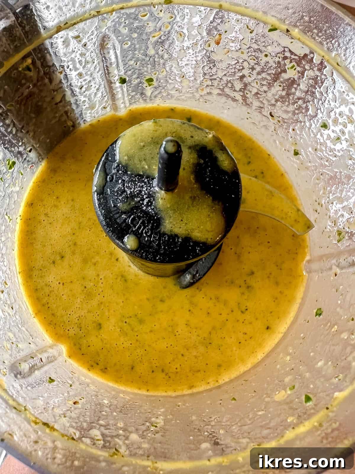 Smooth, golden-yellow salad dressing with turmeric and mint, blended and ready in a food processor.