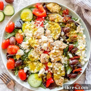 A beautifully presented Grilled Chicken Greek Salad in a large plate with dressing on top, ready to be enjoyed.