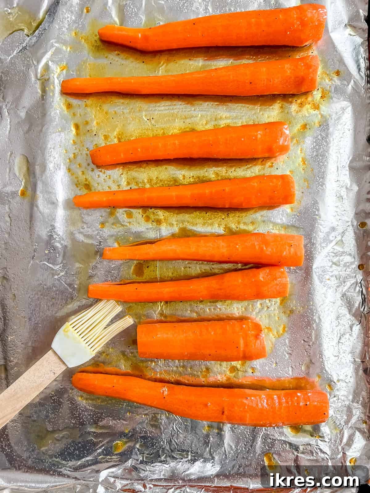 Sunshine Maple Glazed Carrots 5 Carrots arranged on a greased baking sheet, freshly coated with the maple turmeric glaze.
