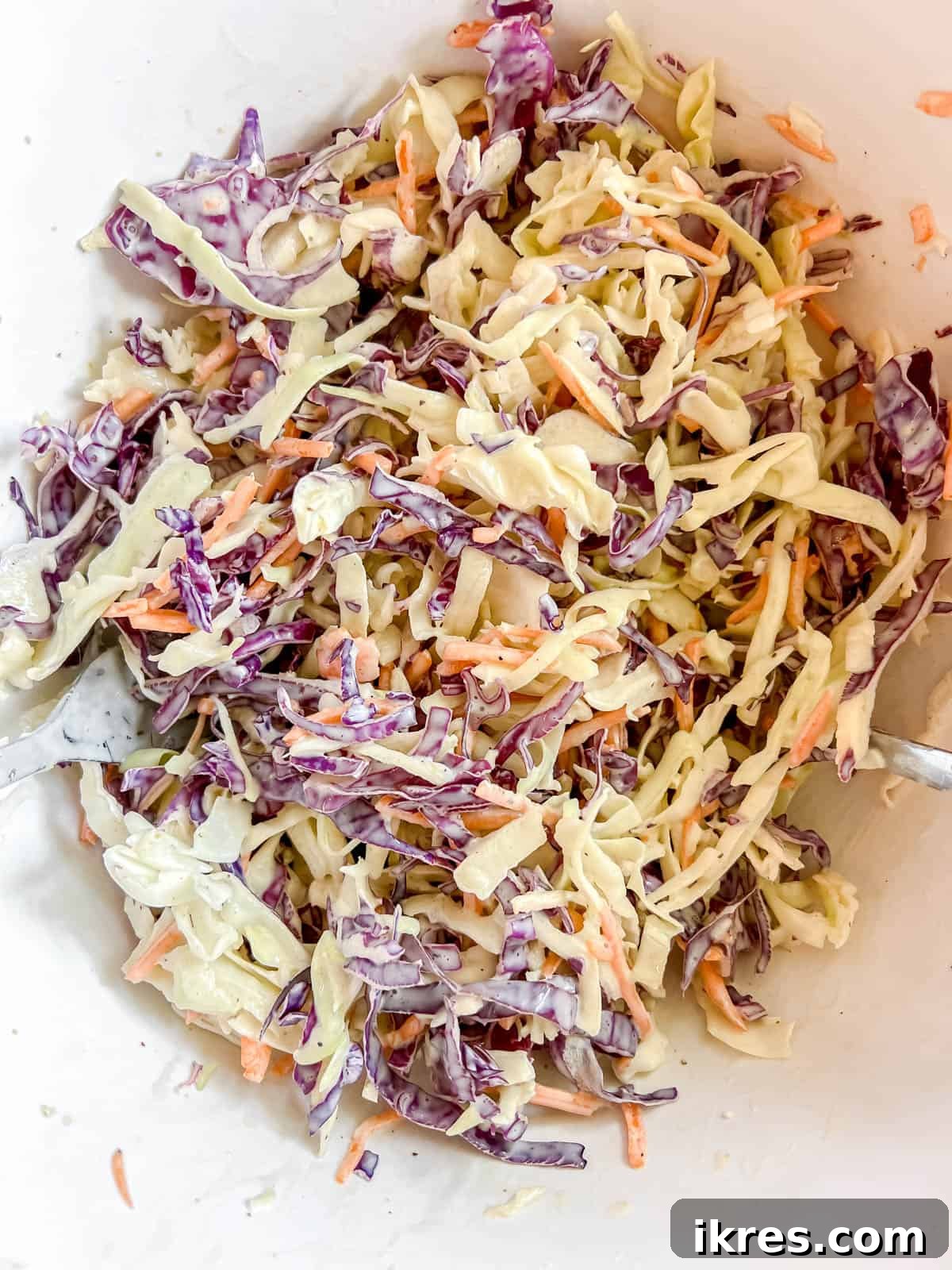 Dressing fully mixed into the cabbage and carrots, ready to be served.