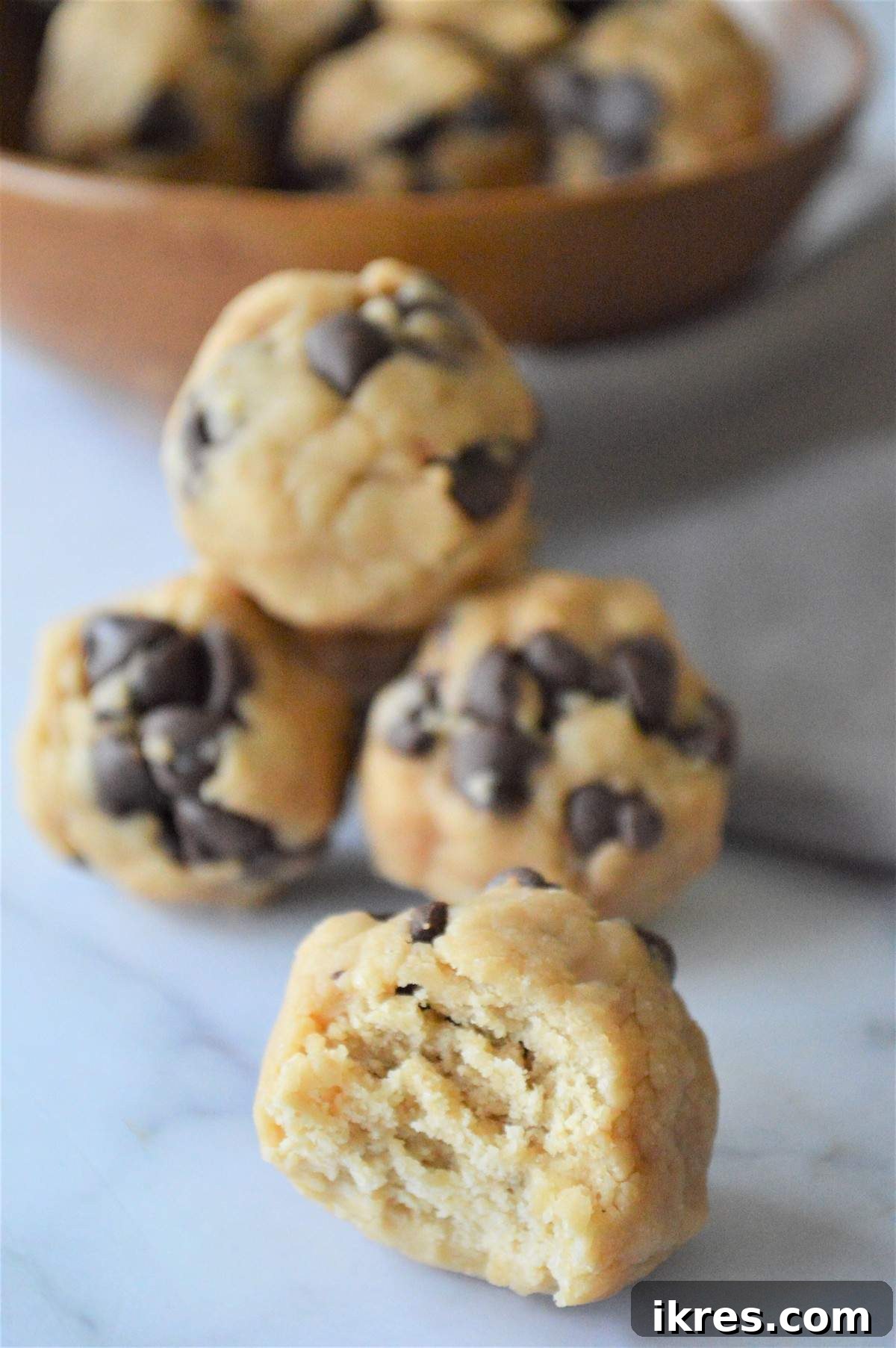 Easy No-Bake Power Bites 4 A delightful pile of no bake energy bites, with a rustic bowl of extra ingredients in the background, hinting at customization possibilities.